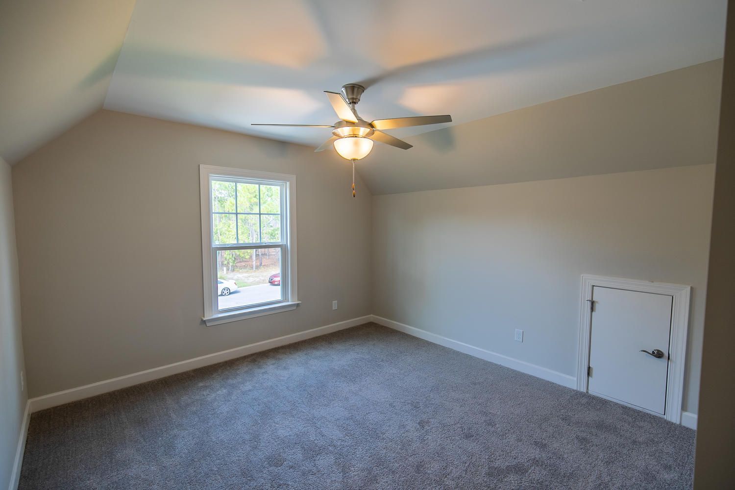 An empty bedroom with a ceiling fan and a window.