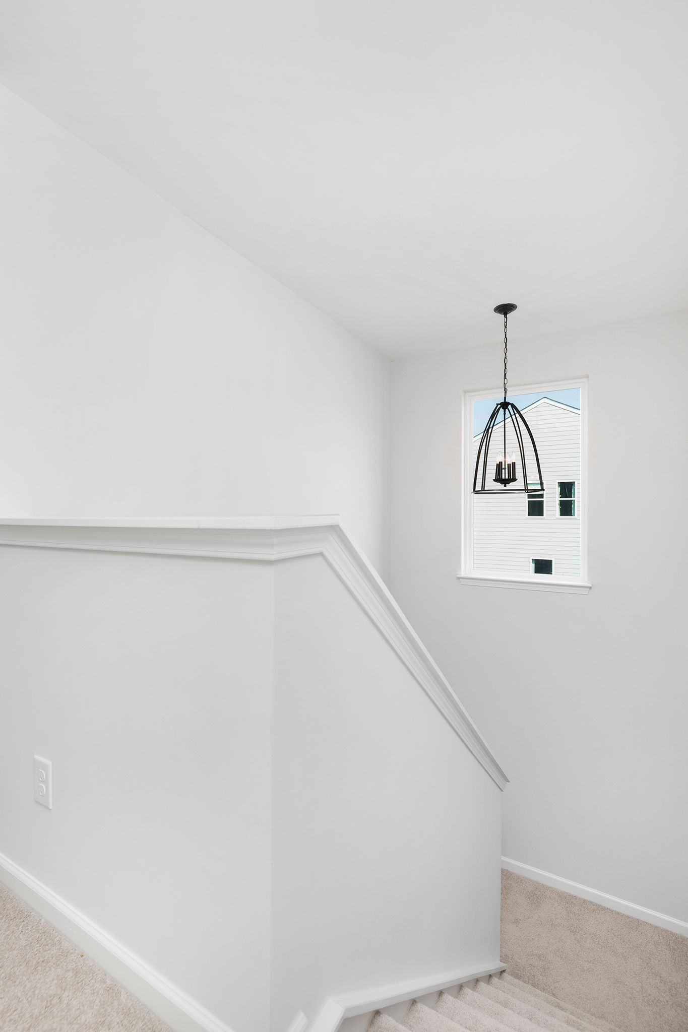 A staircase with a window and a chandelier hanging from the ceiling.