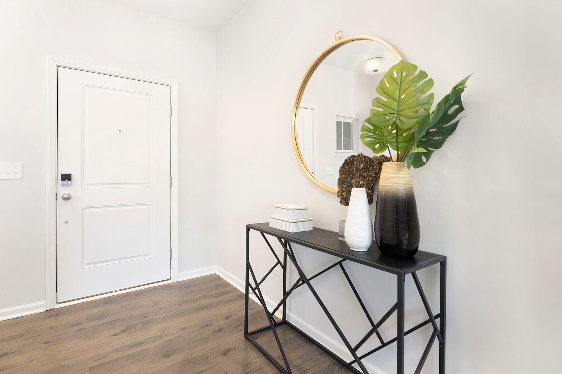 A hallway with a table , mirror and vases.