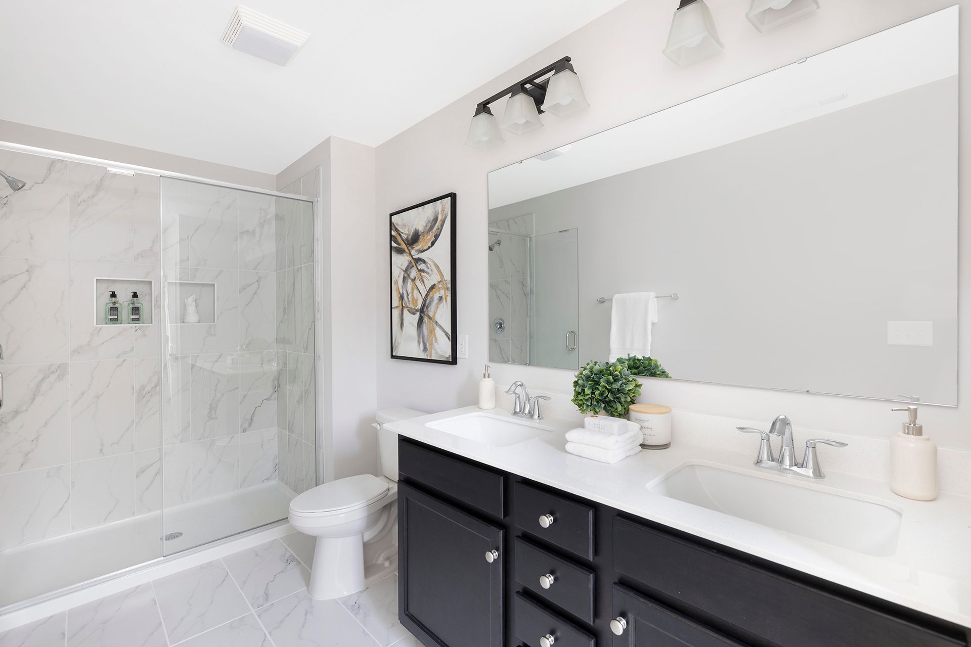 A bathroom with two sinks , a toilet , and a shower.