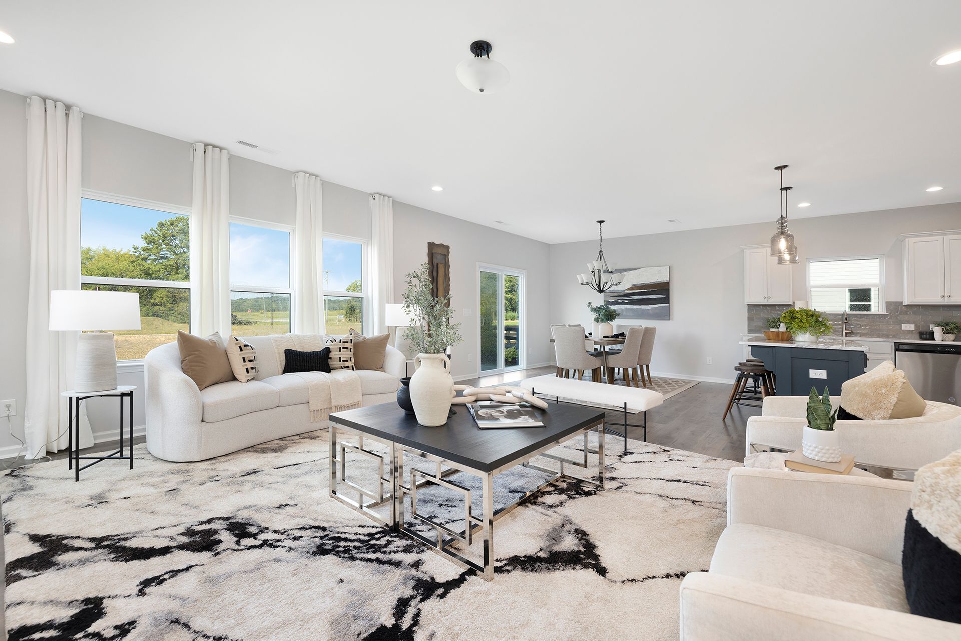A living room with a couch , chairs , a coffee table and a rug.