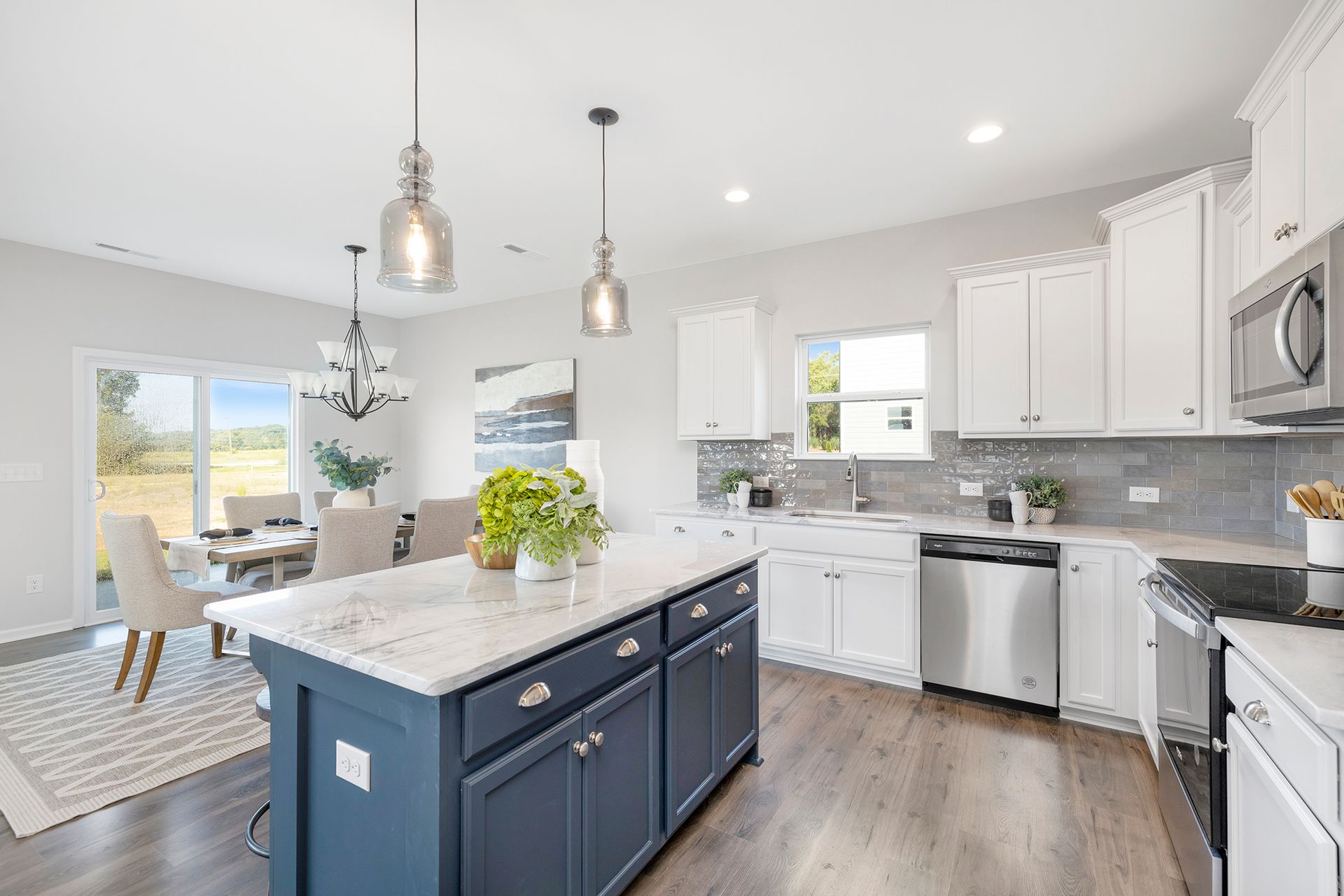 A kitchen with white cabinets , stainless steel appliances , and a large island.