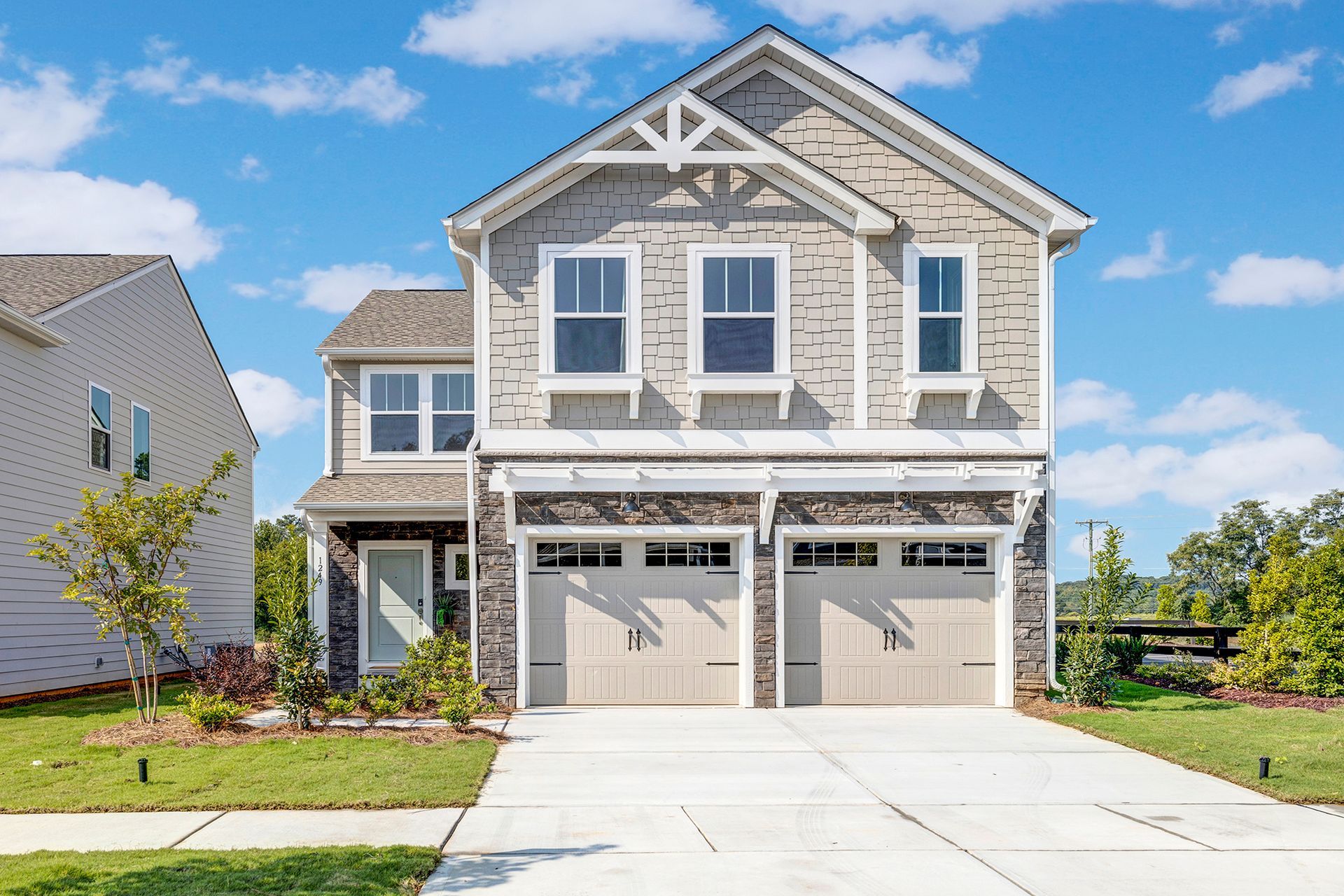 A large house with two garages and a driveway in front of it.