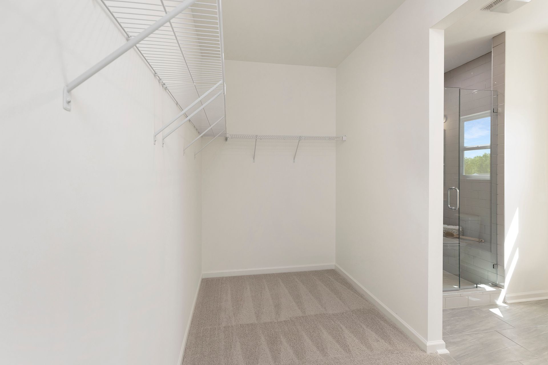 An empty walk in closet in a house with a walk in shower.