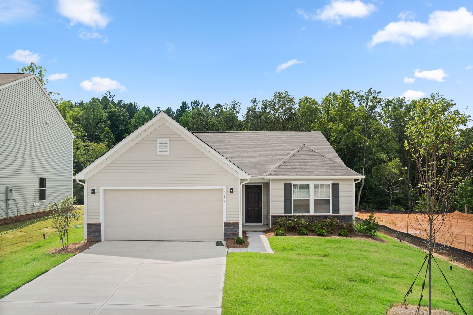 A house with a large garage and a lush green lawn in front of it.
