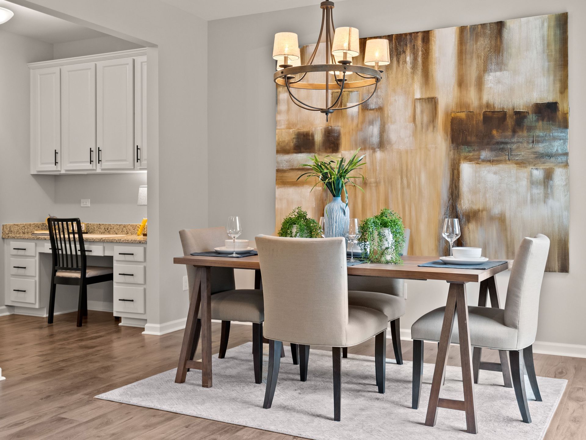 A dining room with a table and chairs and a large painting on the wall.