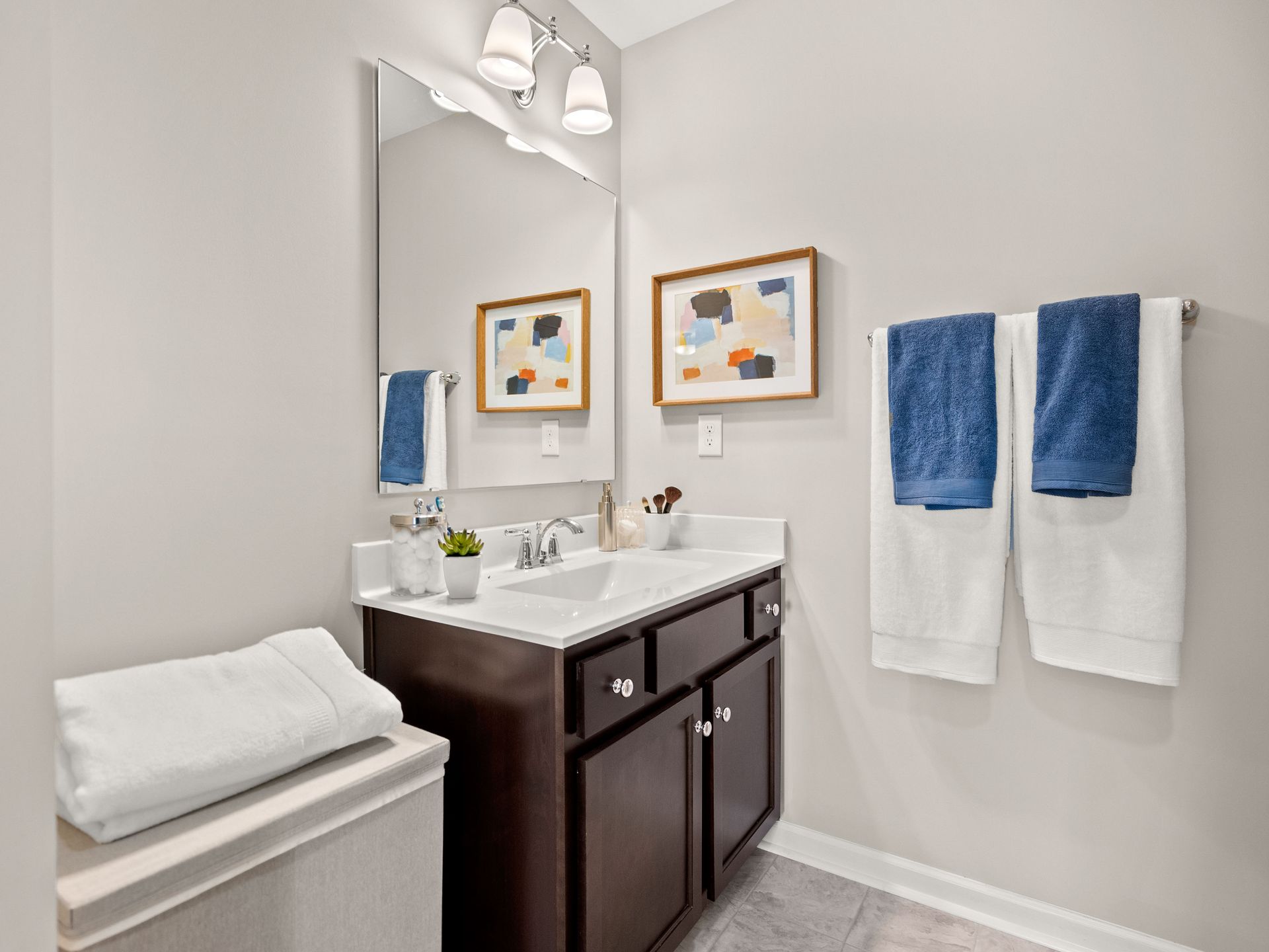 A bathroom with a sink , mirror and towels hanging on the wall.