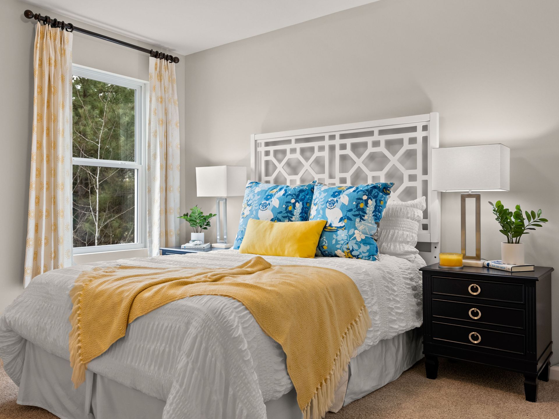 A bedroom with a bed , nightstand , lamps and a window.