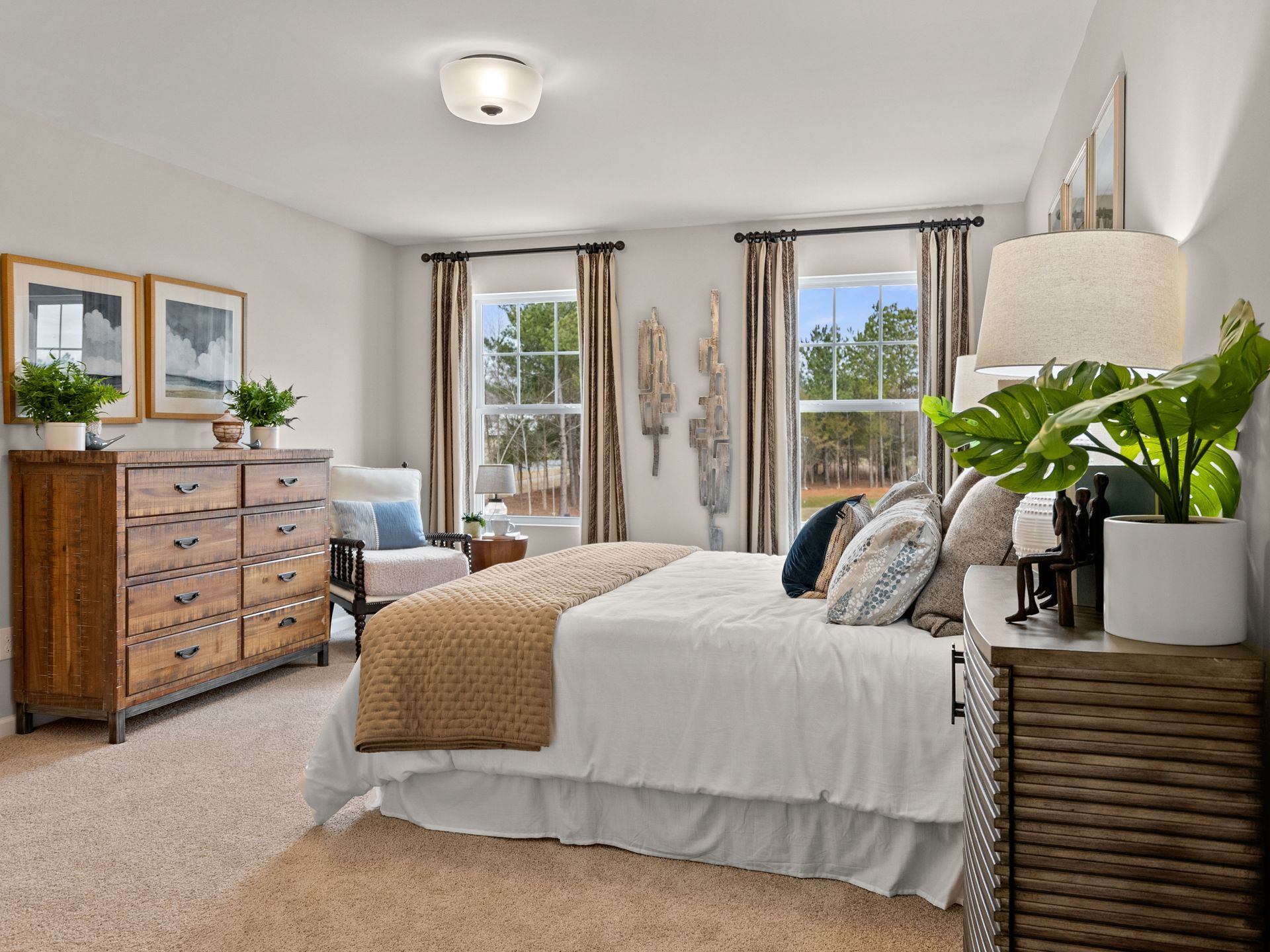 A bedroom with a king size bed , dresser , nightstand and two windows.
