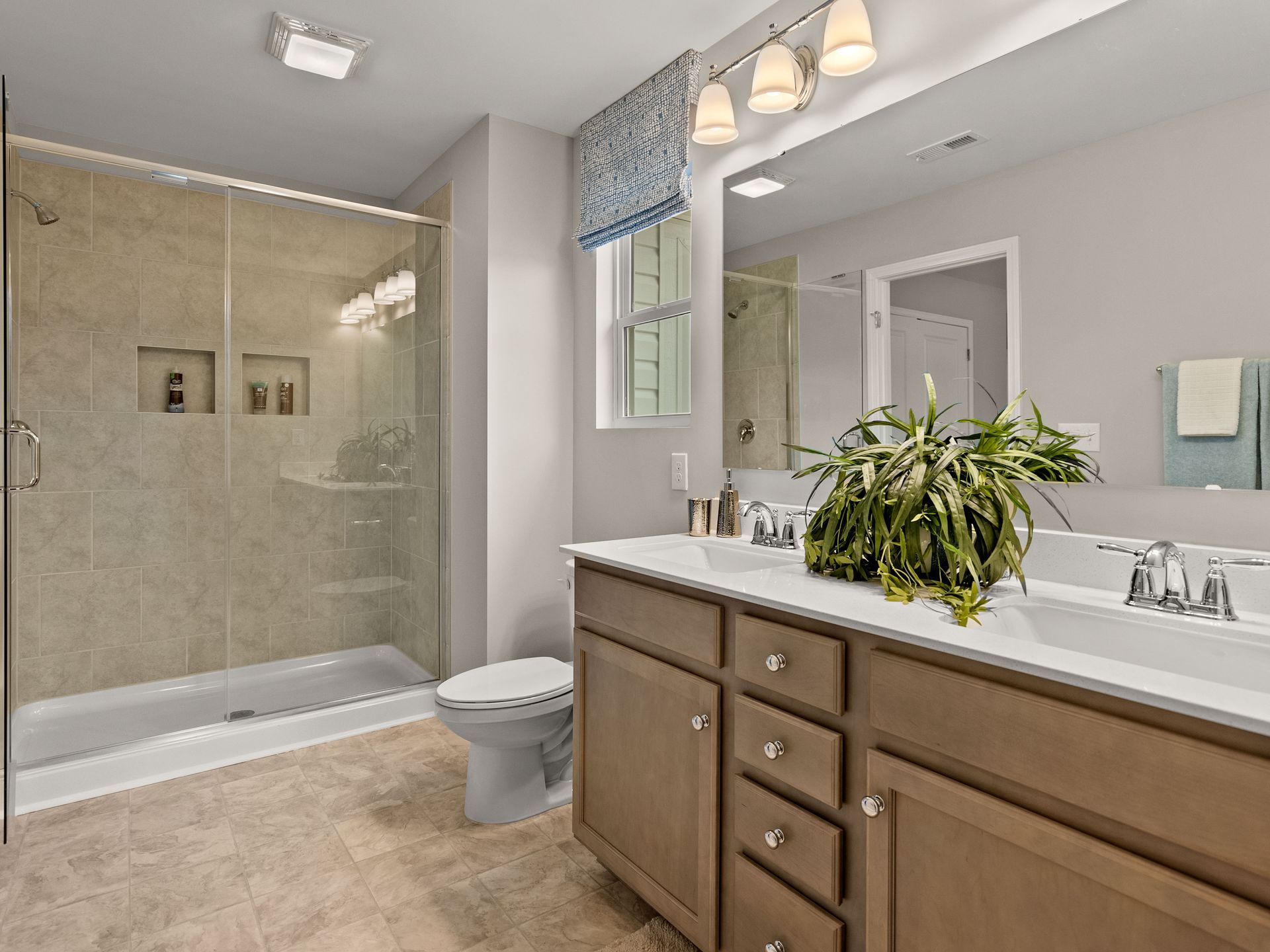 A bathroom with two sinks , a toilet , and a walk in shower.