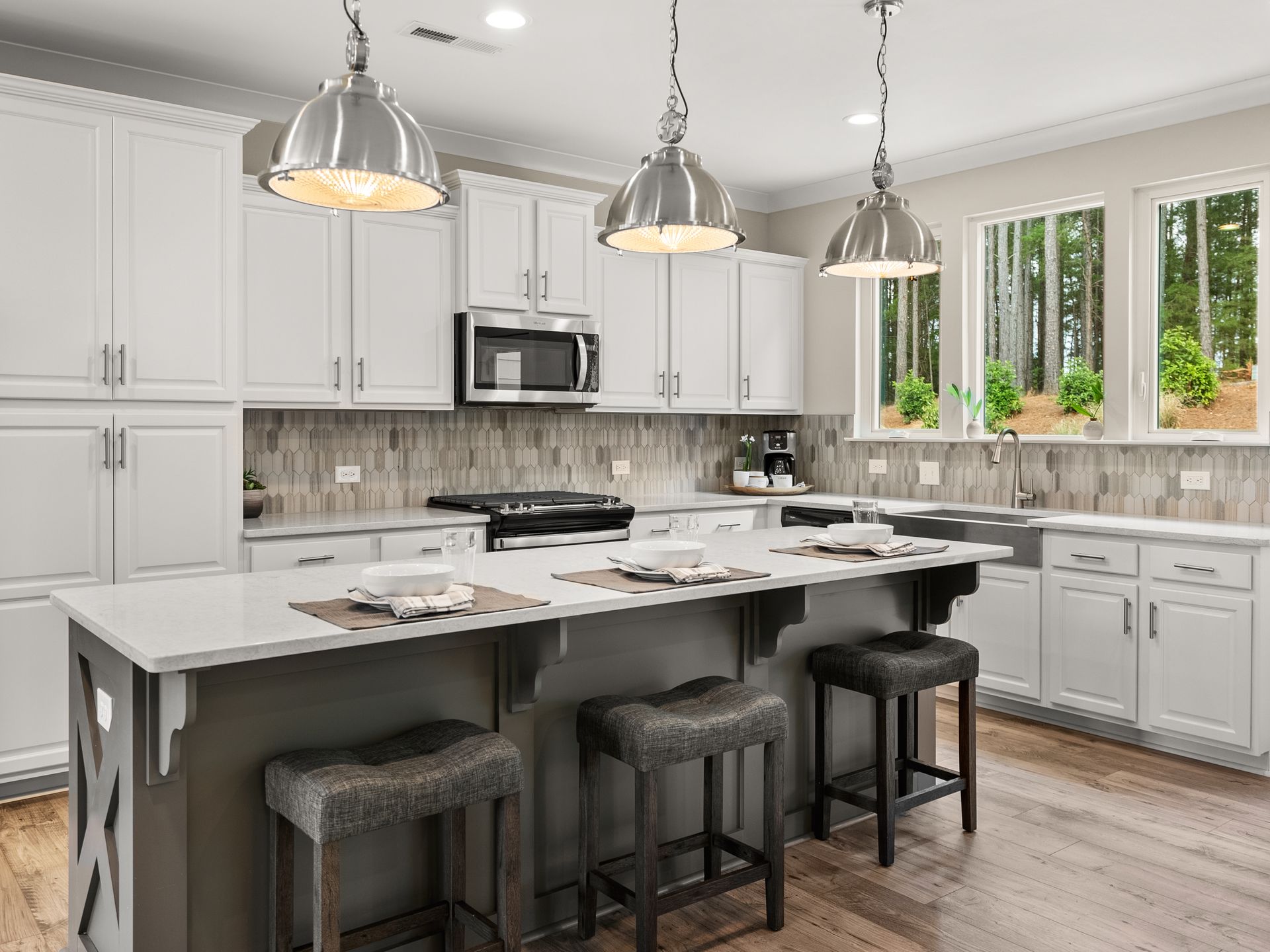 A kitchen with white cabinets , stainless steel appliances , and a large island.