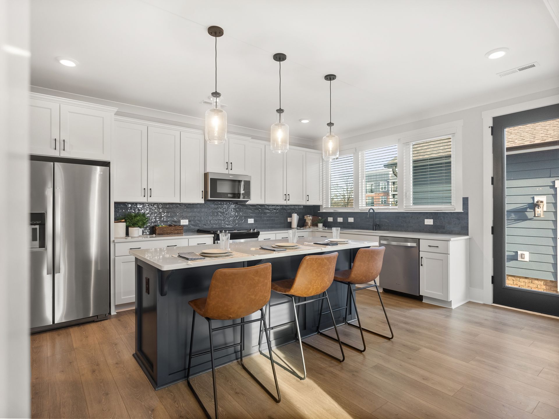 A kitchen with white cabinets , stainless steel appliances , and a large island.