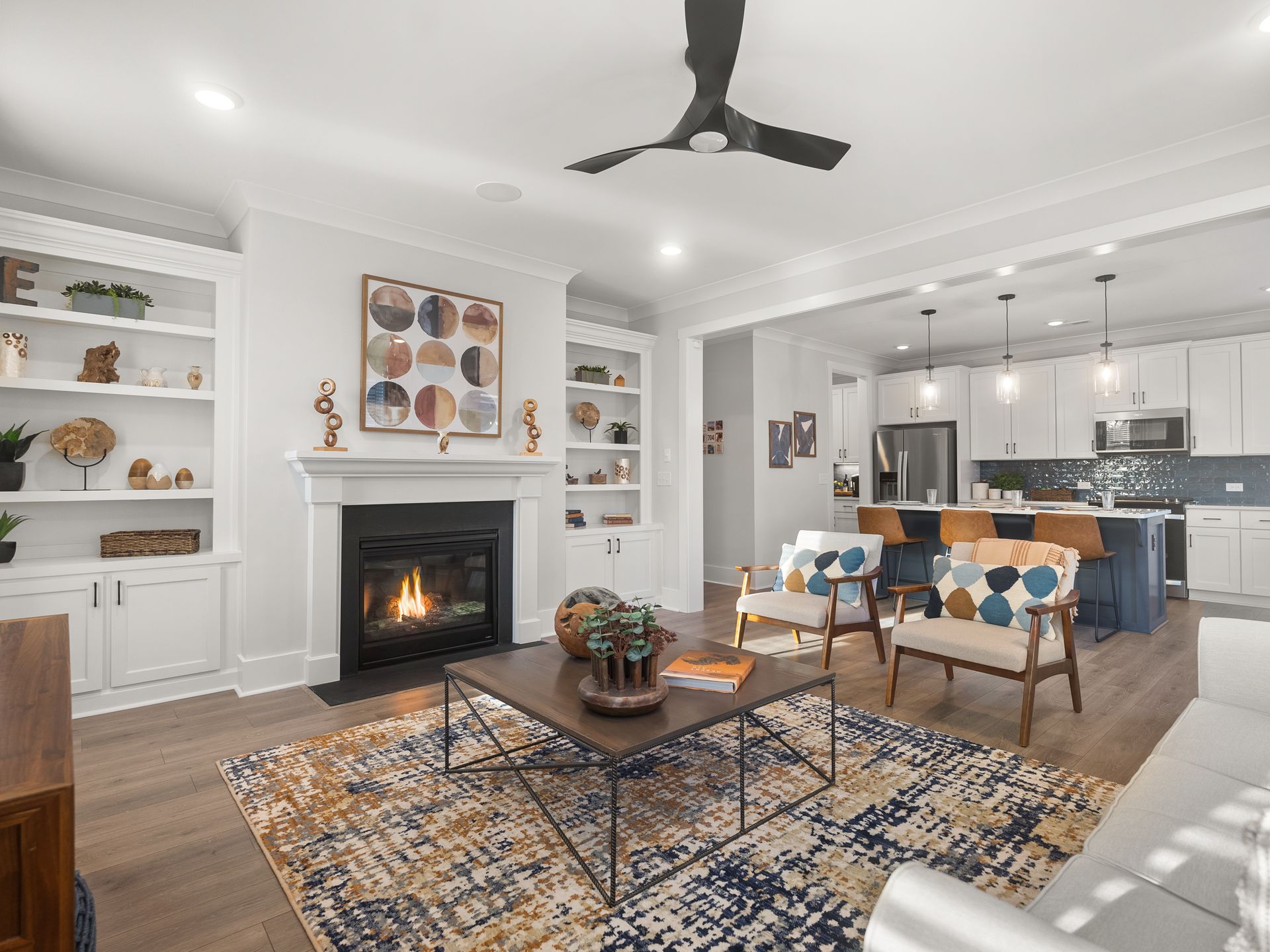 A living room with a fireplace , coffee table , chairs and a ceiling fan.