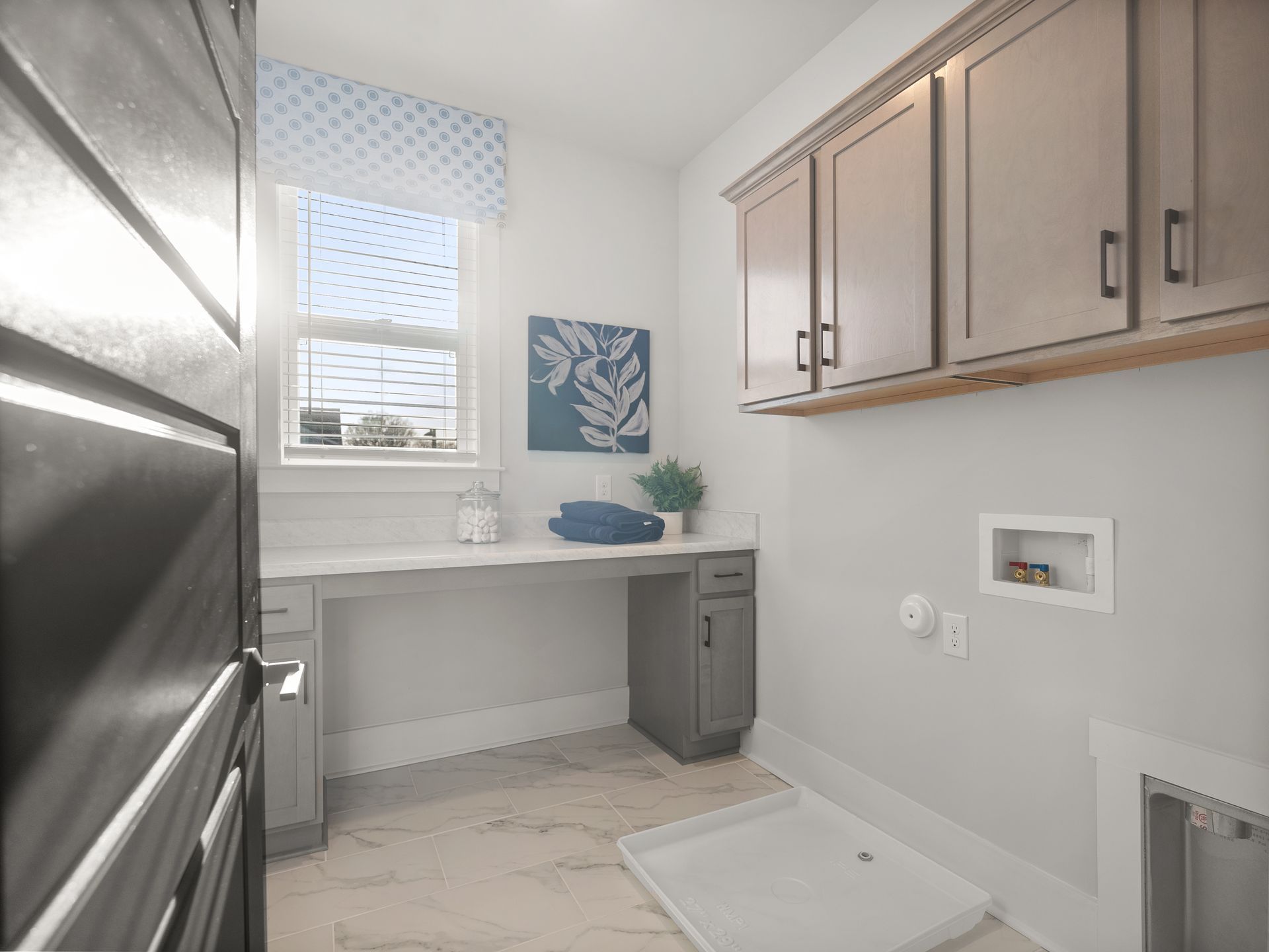 A laundry room with a sink , cabinets , and a window.