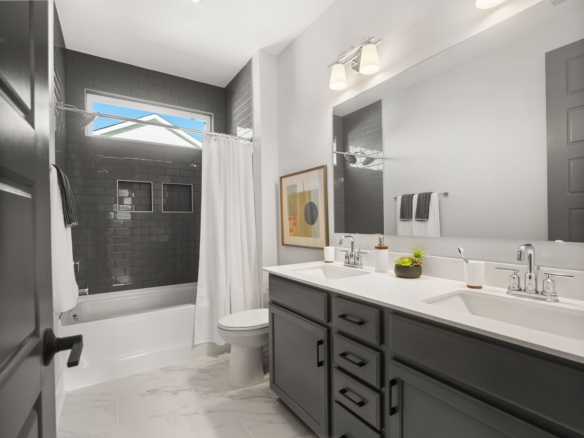 A bathroom with two sinks , a toilet , and a shower.