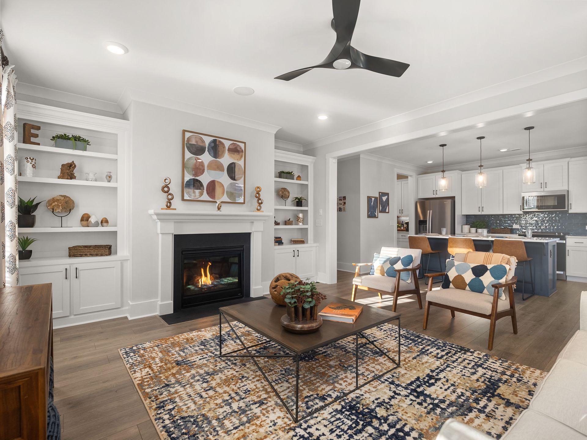 A living room with a fireplace , coffee table , chairs and a ceiling fan.