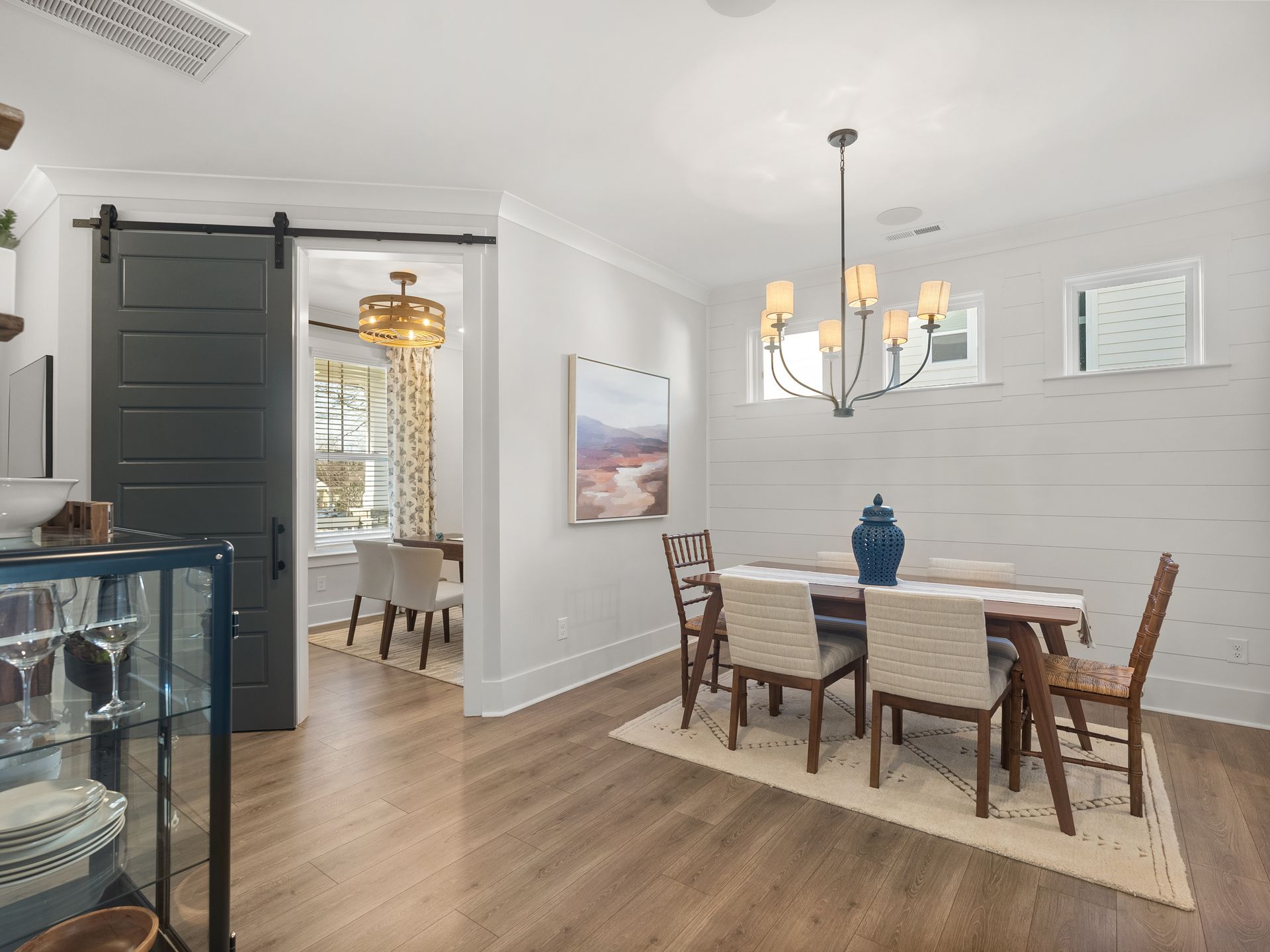 A dining room with a table and chairs and a sliding barn door.