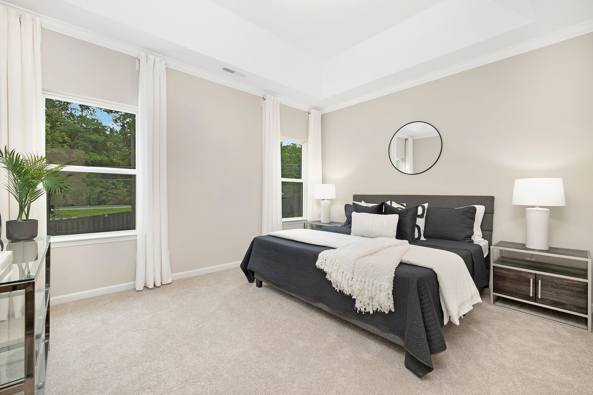 A bedroom with a large bed , nightstands , lamps and a mirror.