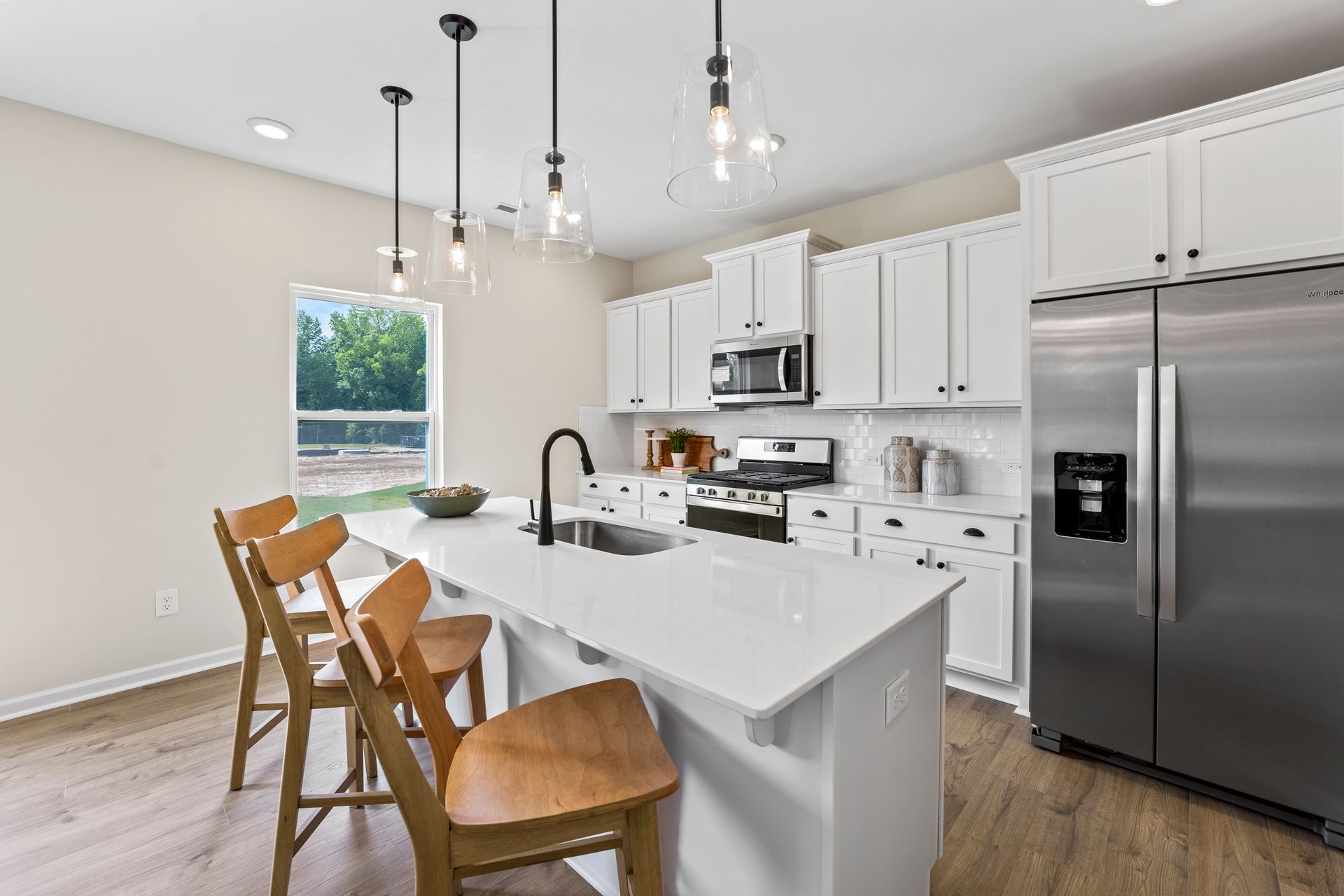 a kitchen with white cabinets , stainless steel appliances , and a large island .