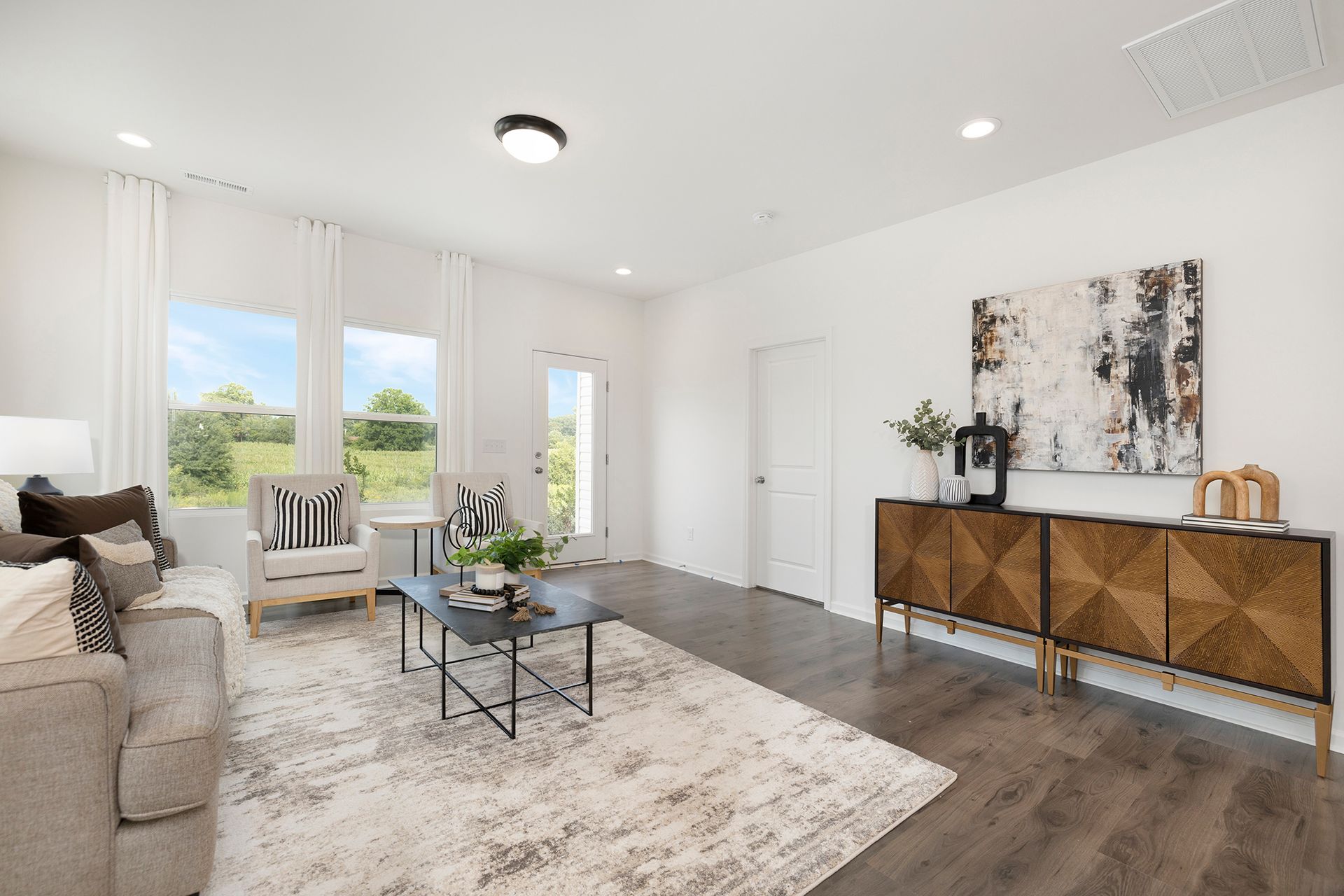 A living room with a couch , chair , coffee table , and dresser.