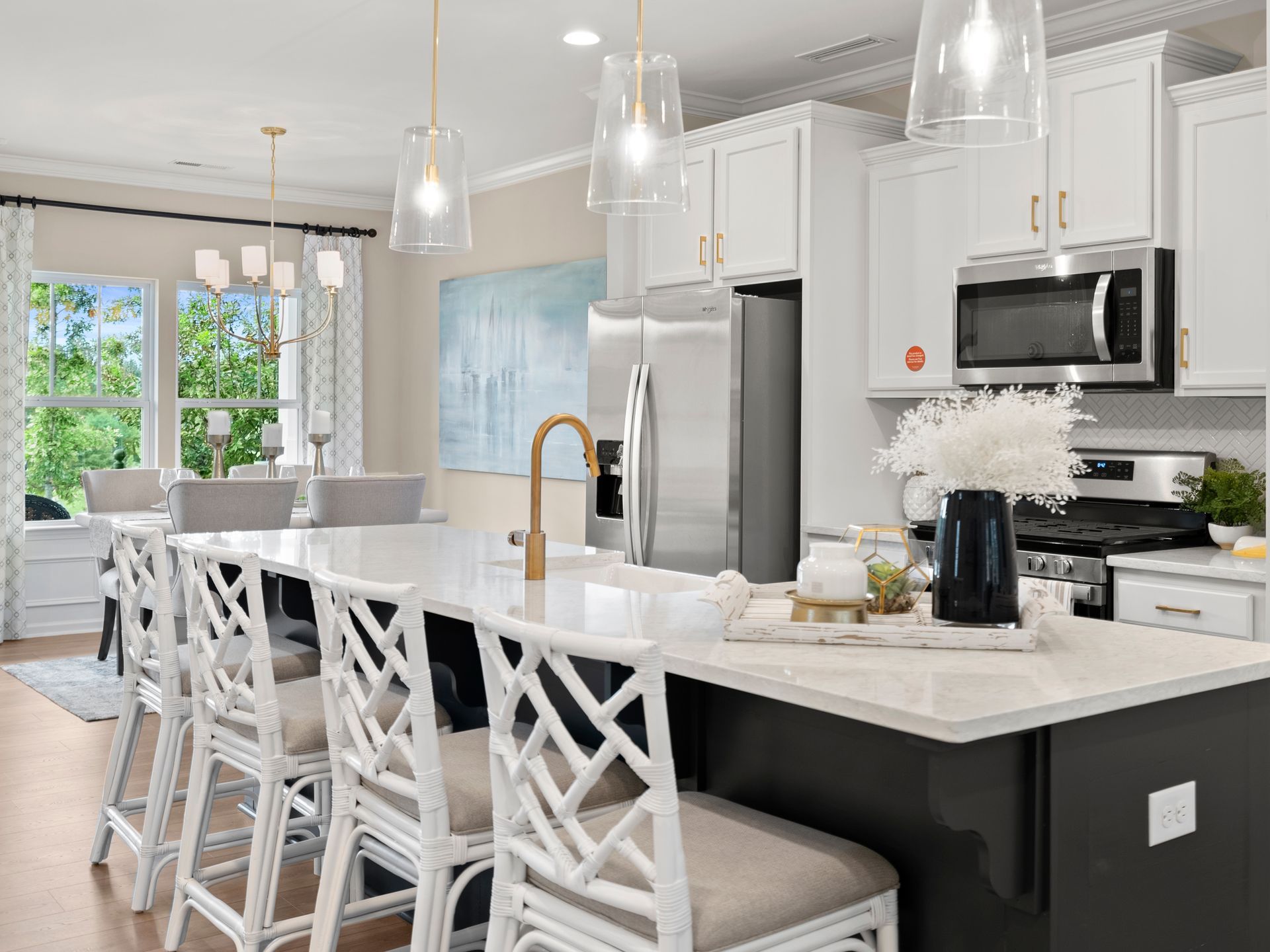 A kitchen with white cabinets , stainless steel appliances , and a large island.