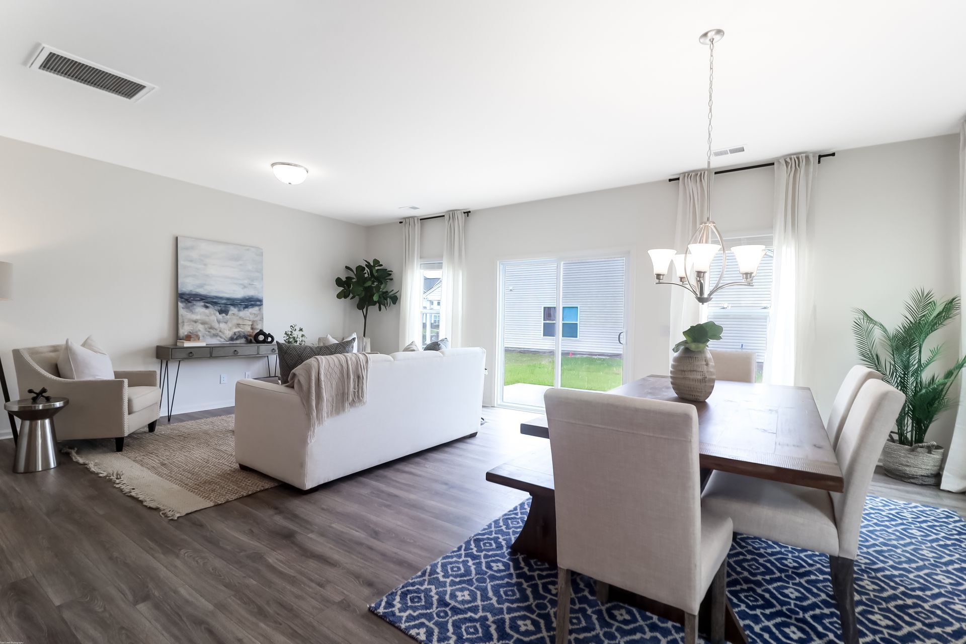 A living room with a couch , chairs , a table and a chandelier.