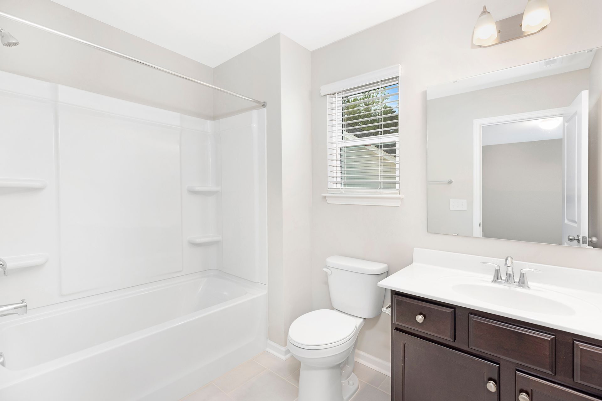 A bathroom with a toilet , sink , bathtub and mirror.