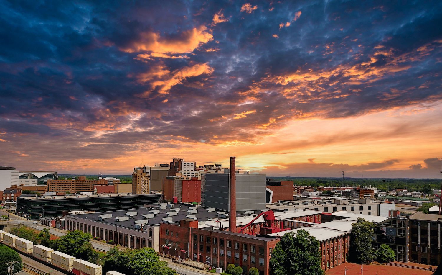 An aerial view of a city at sunset with a train in the foreground.