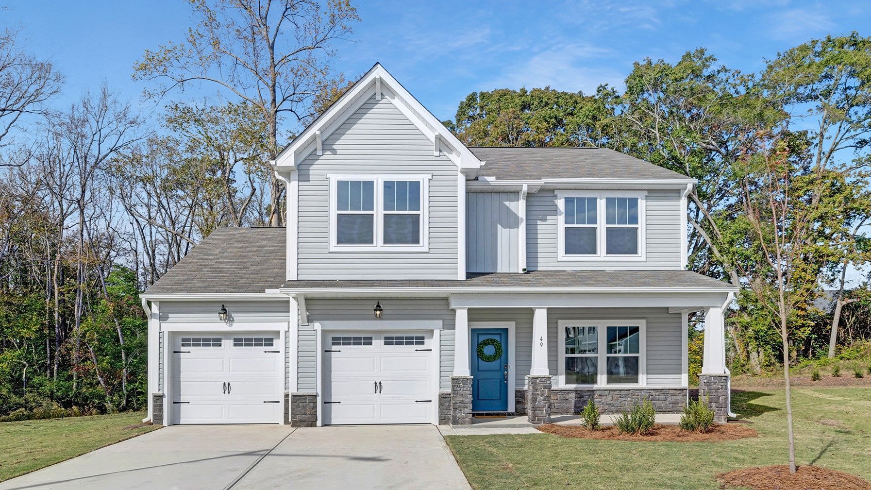 A white house with a blue door and two garages is for sale.