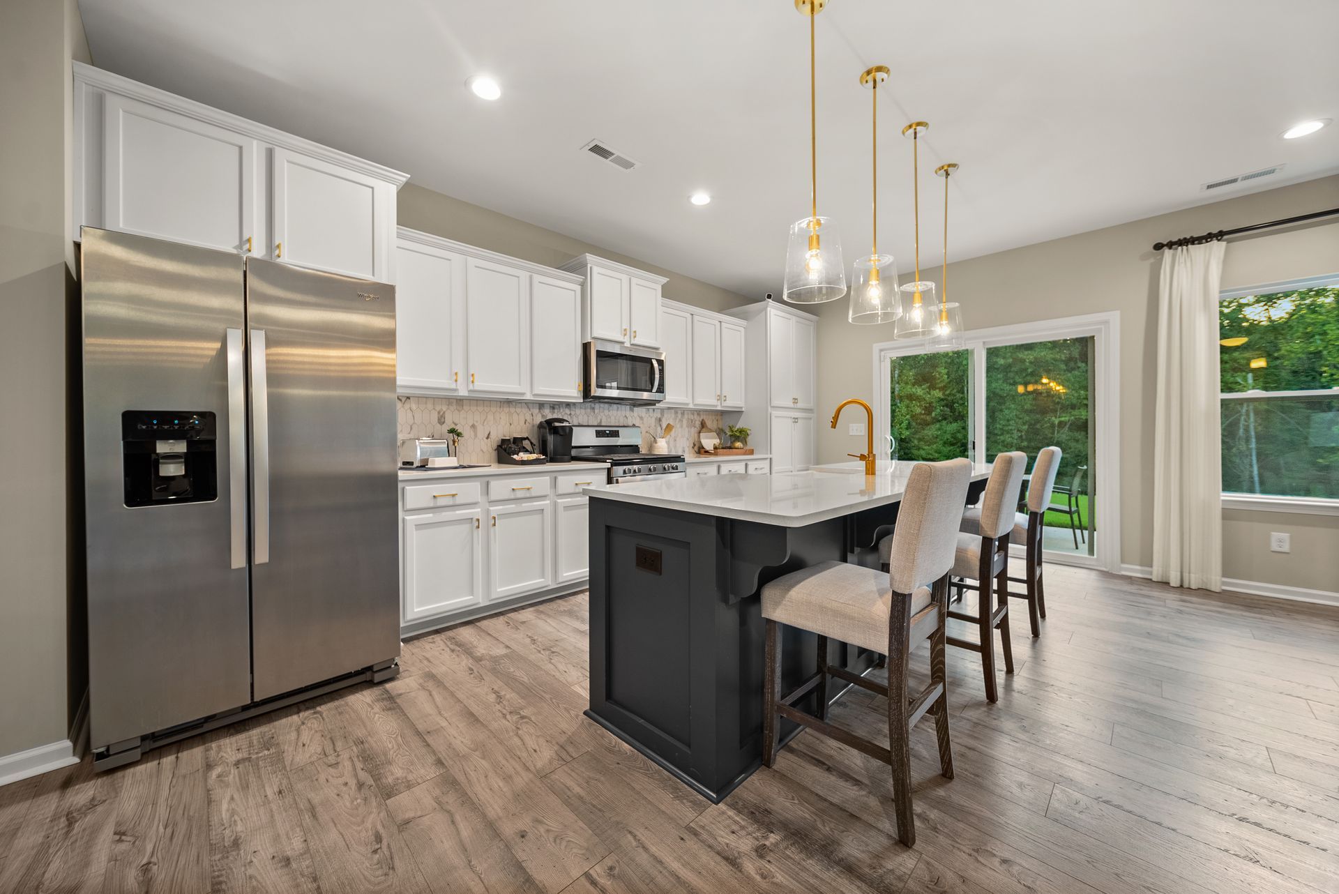 A kitchen with stainless steel appliances , white cabinets , and a large island.