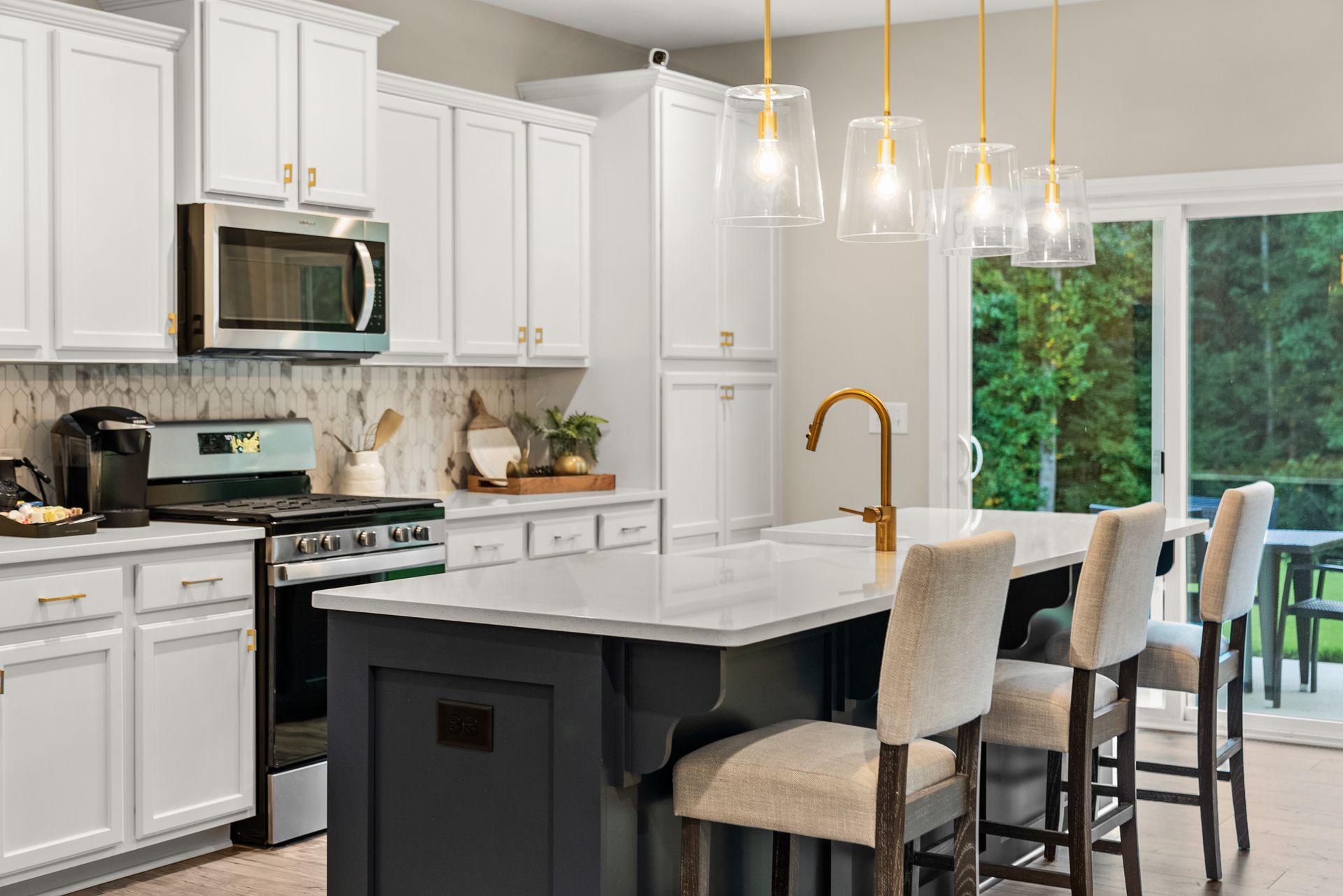 A kitchen with white cabinets , stainless steel appliances , and a large island.