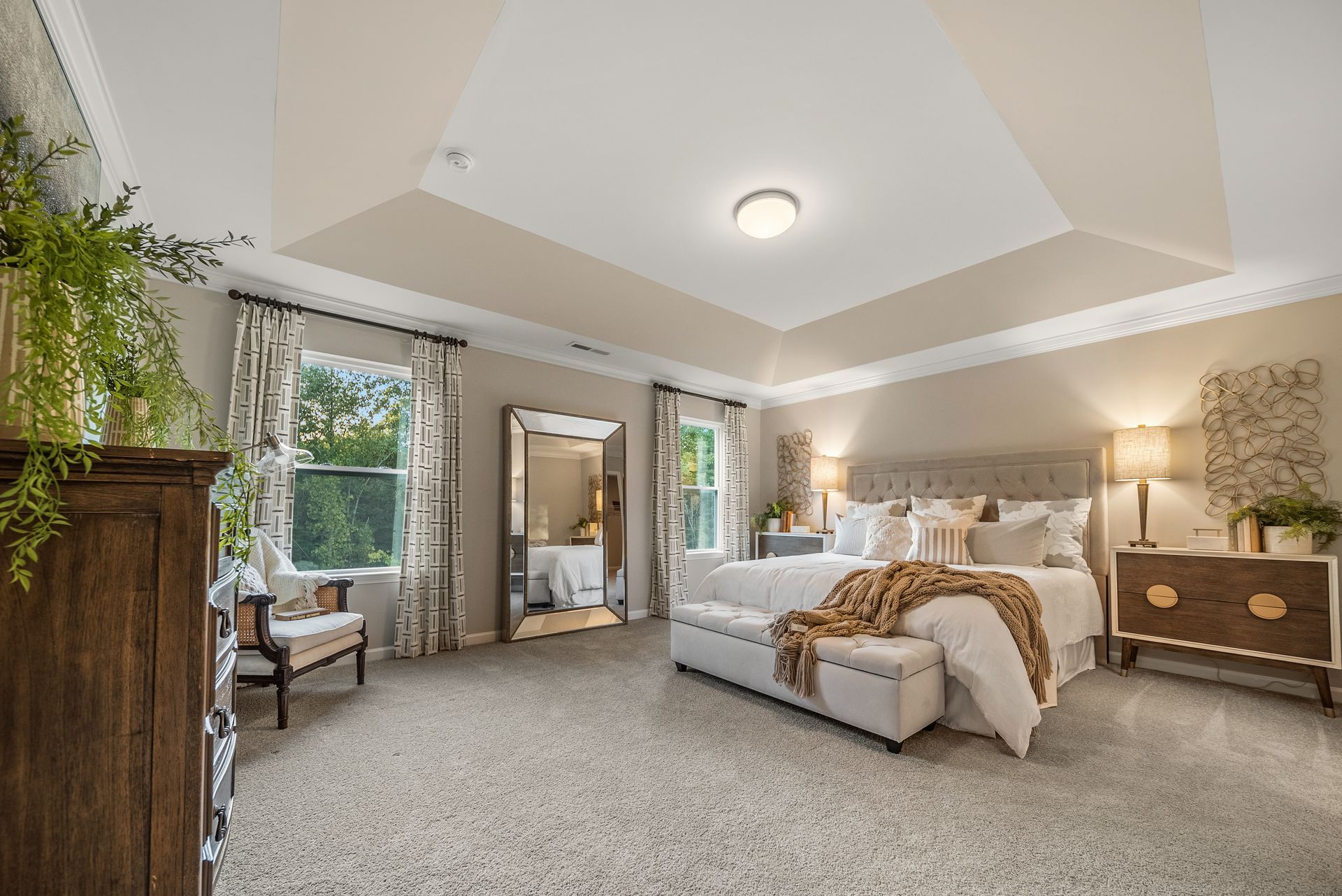 A bedroom with a large bed , dresser , chair and mirror.