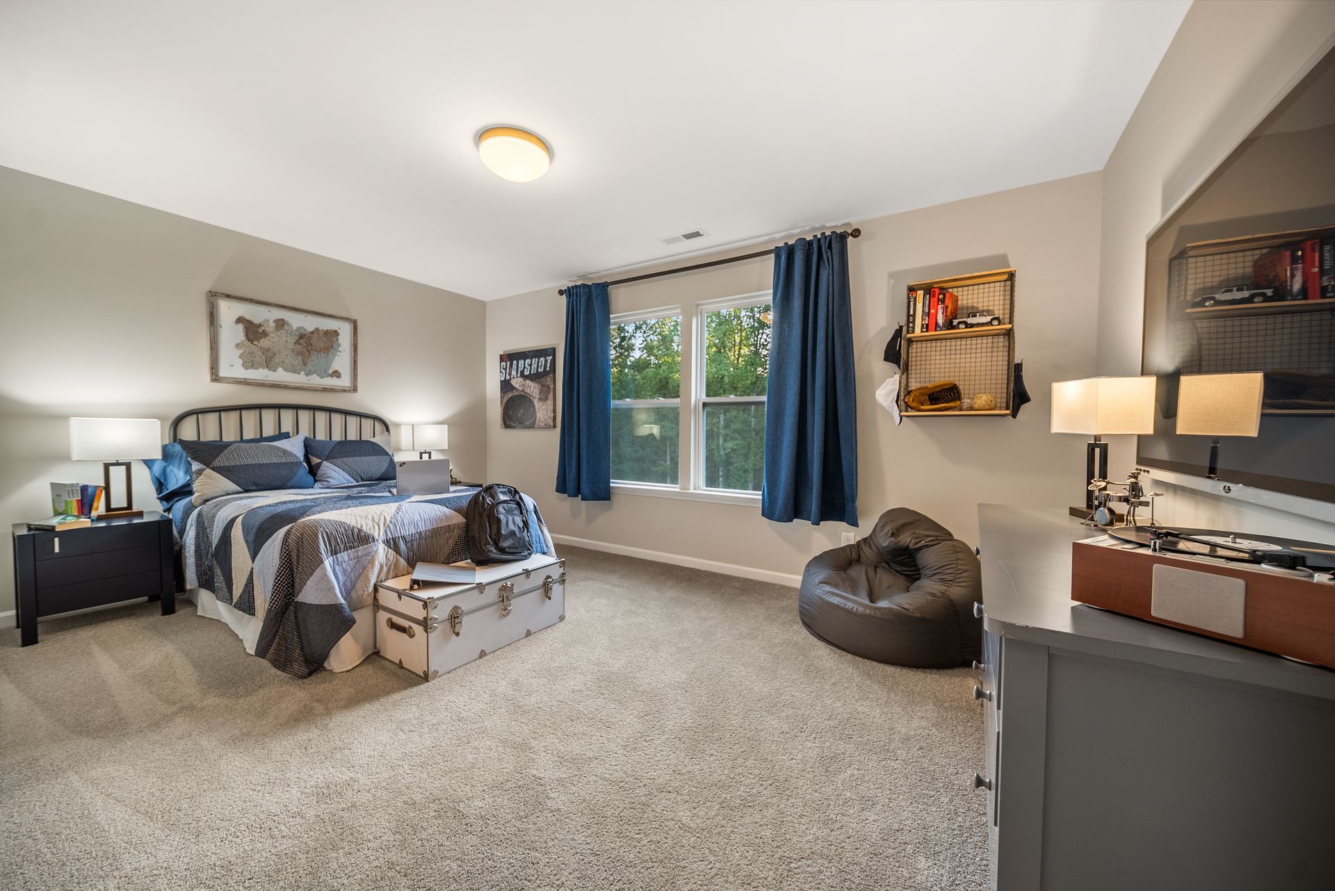A bedroom with a bed , dresser , nightstand , television and window.