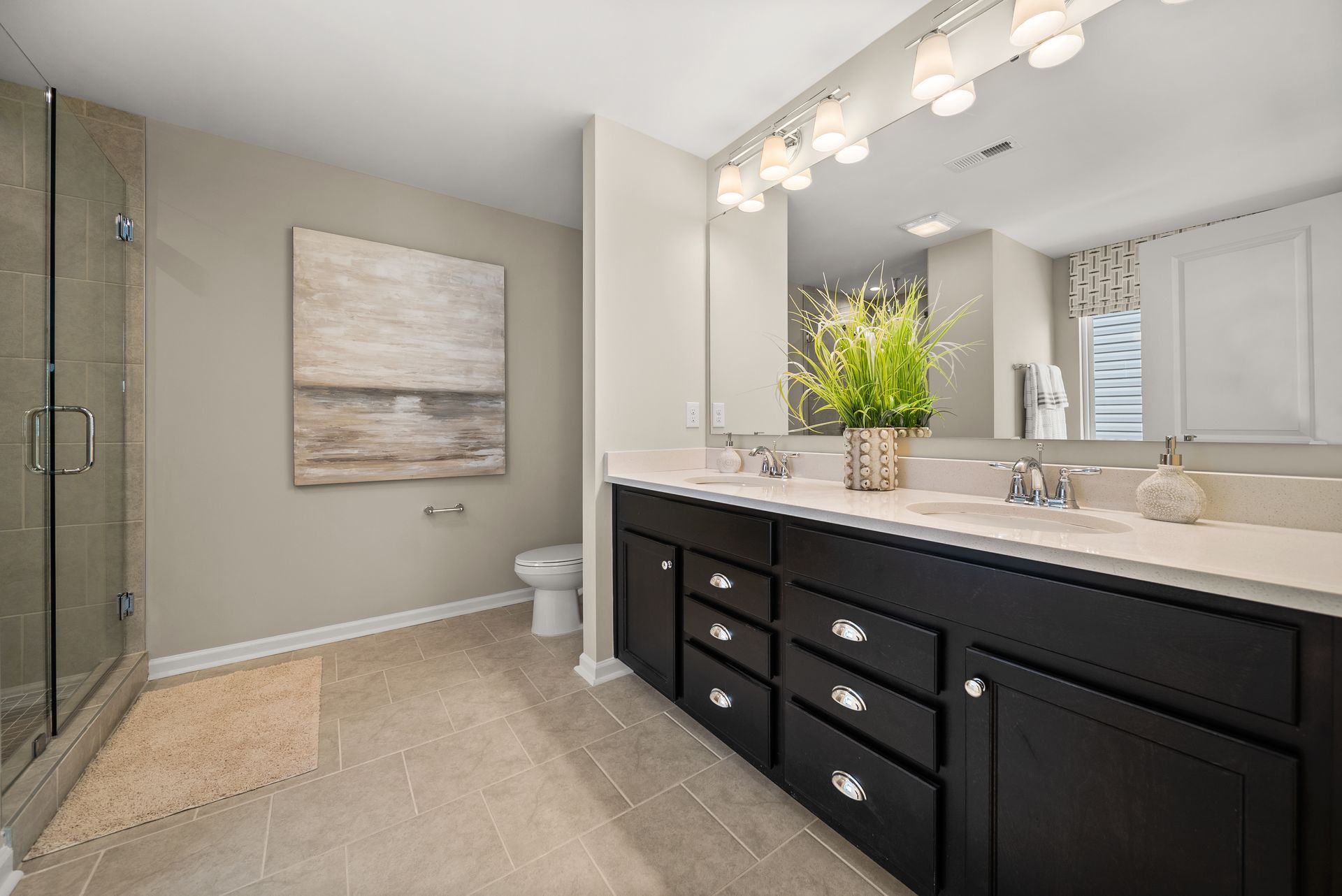 A bathroom with two sinks , a toilet , and a large mirror.