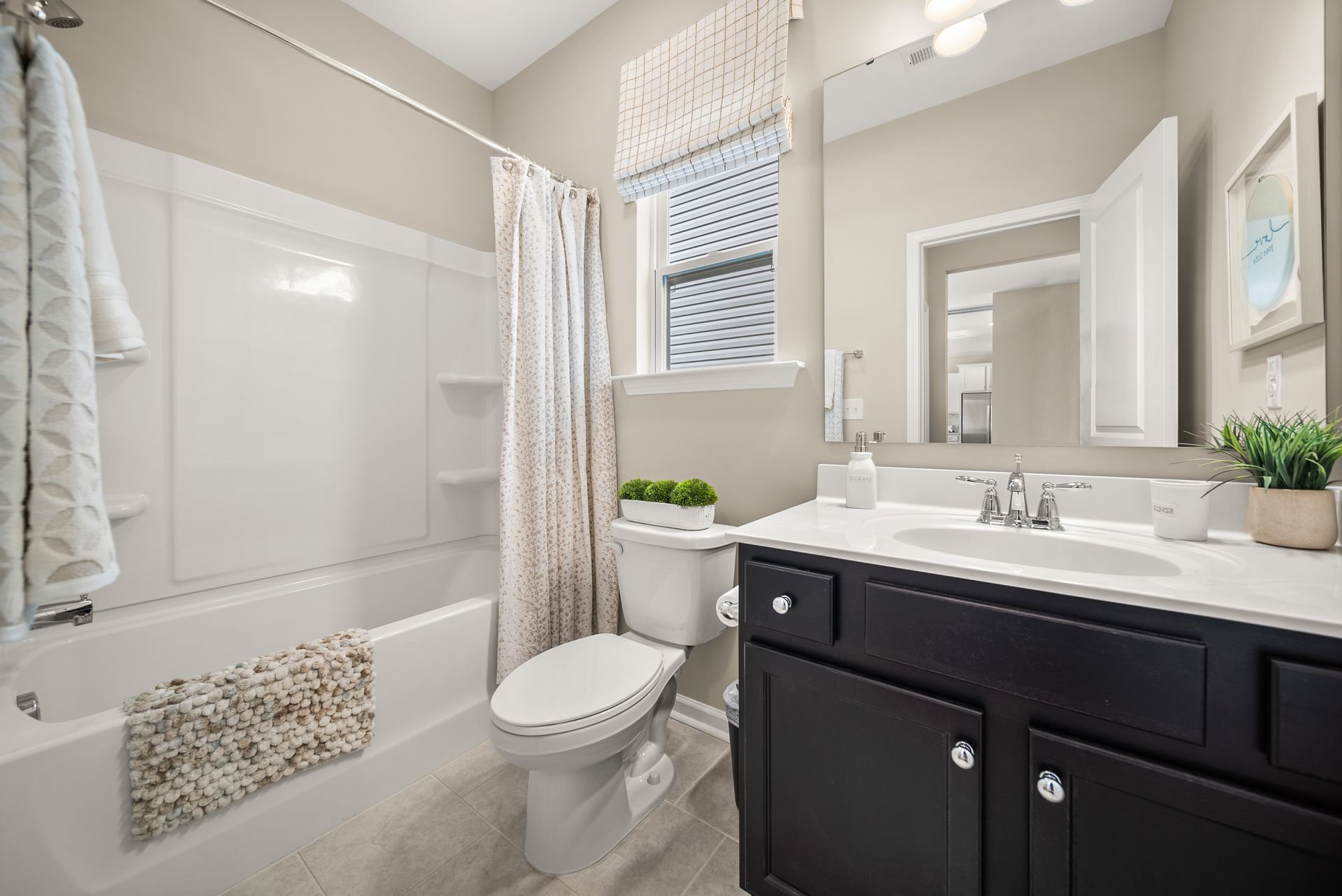 A bathroom with a toilet , sink , tub and mirror.