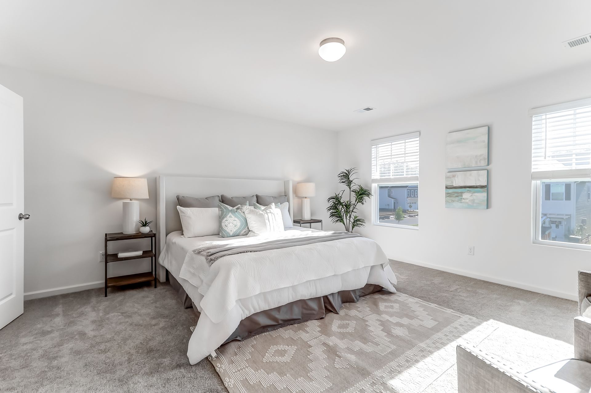 A bedroom with a bed , lamps , nightstands , and a rug.