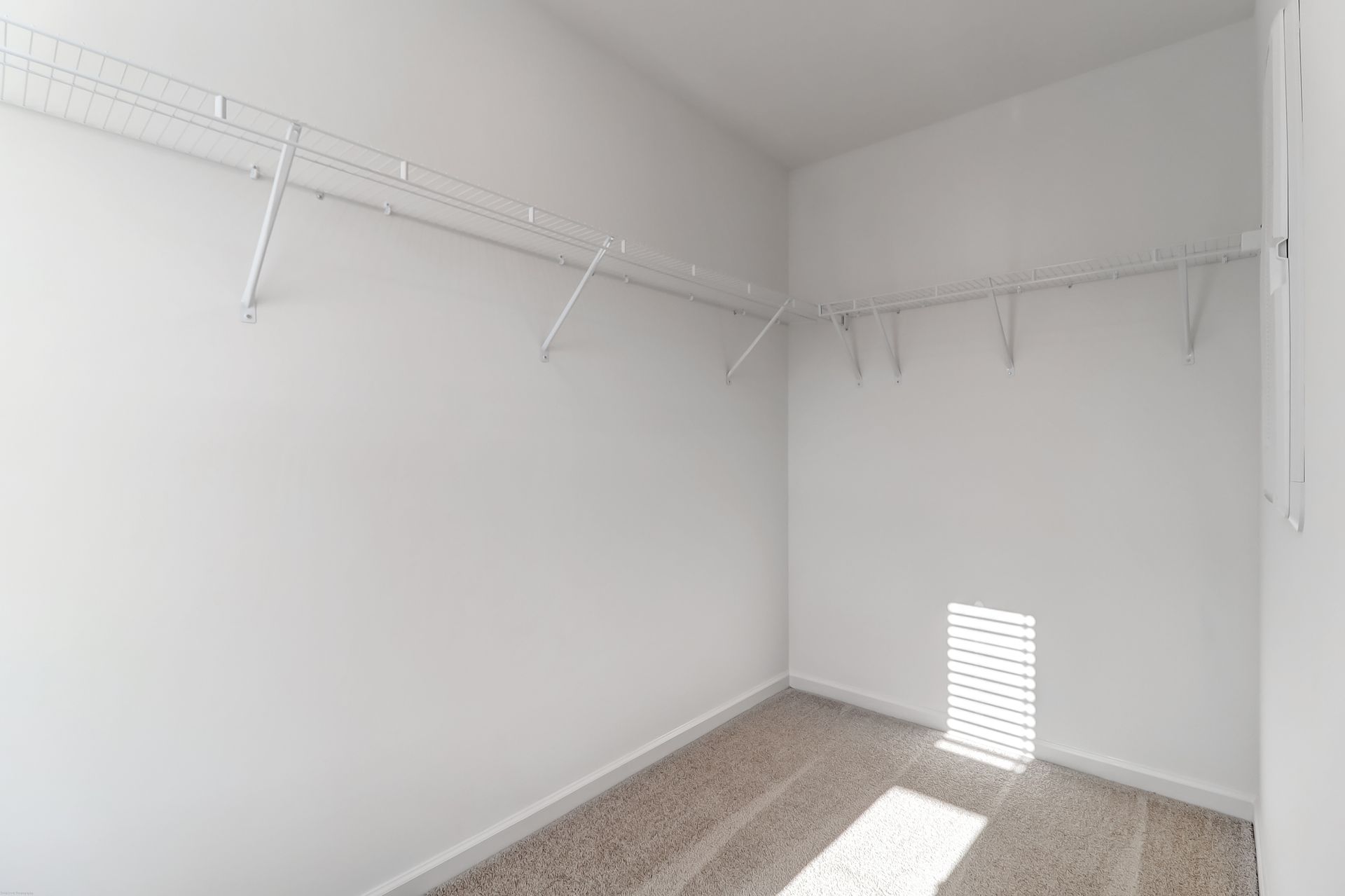 An empty walk in closet with lots of shelves and a window.