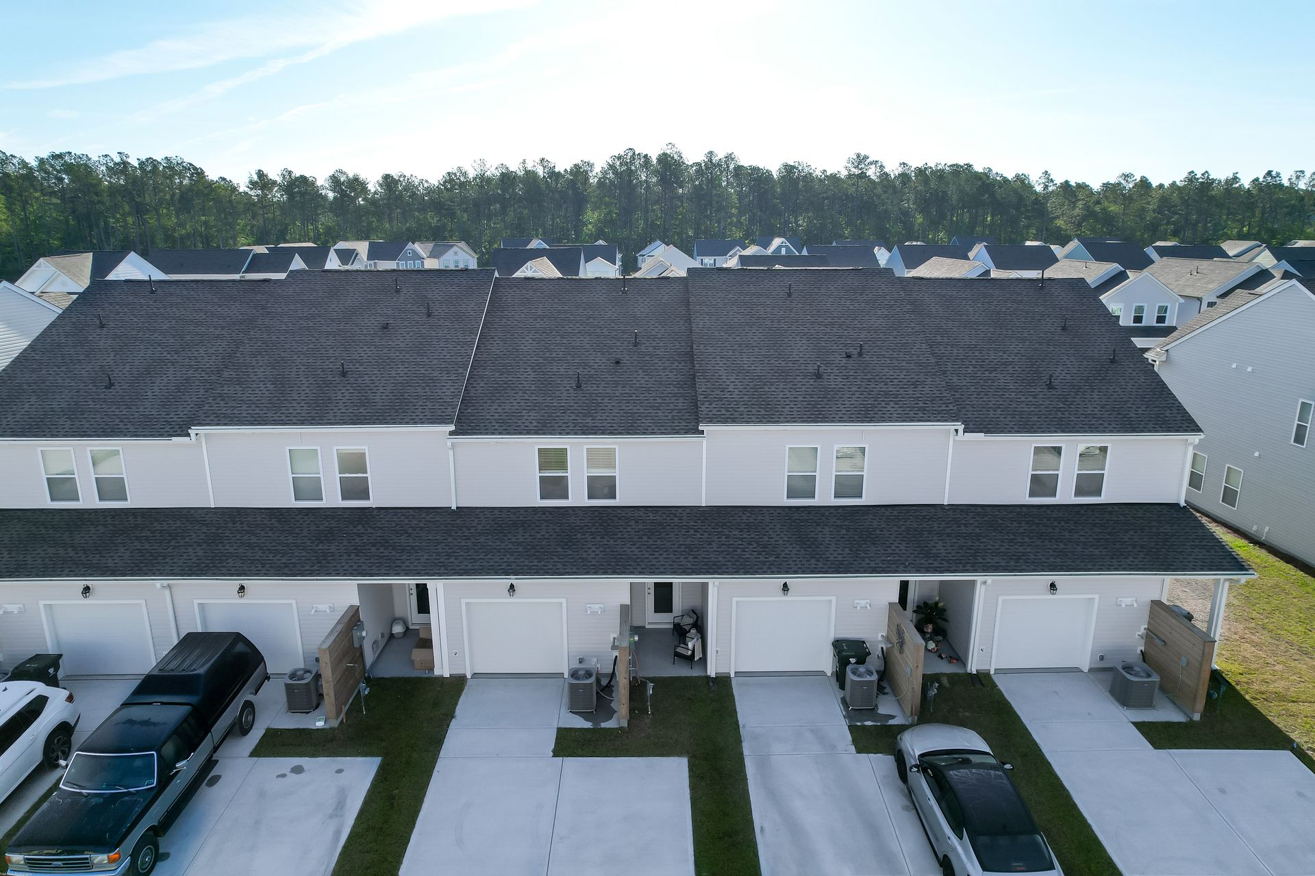 An aerial view of a row of houses with cars parked in front of them