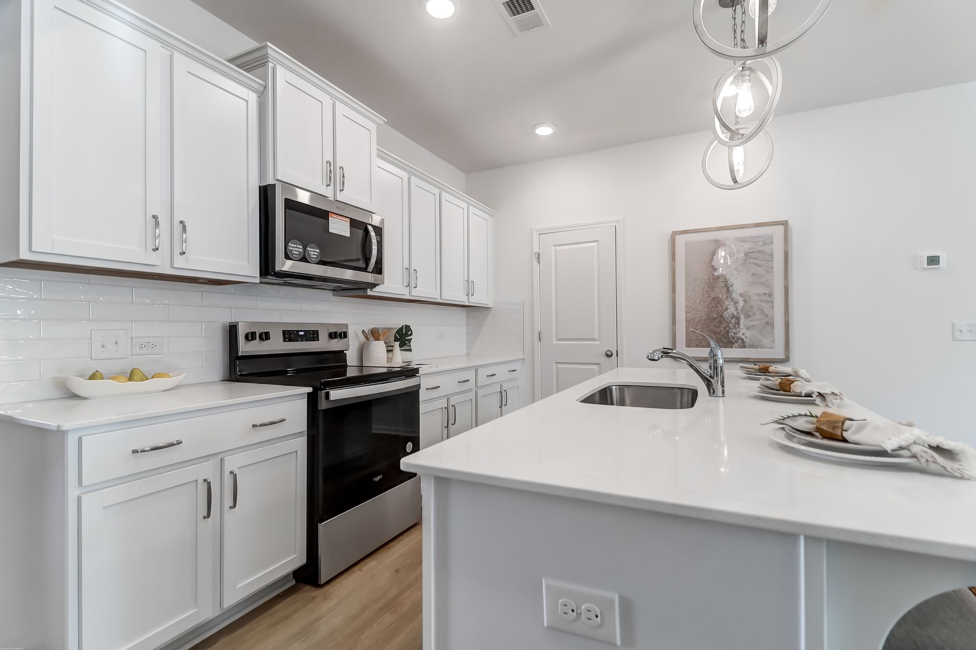 A kitchen with white cabinets , stainless steel appliances , and a large island.
