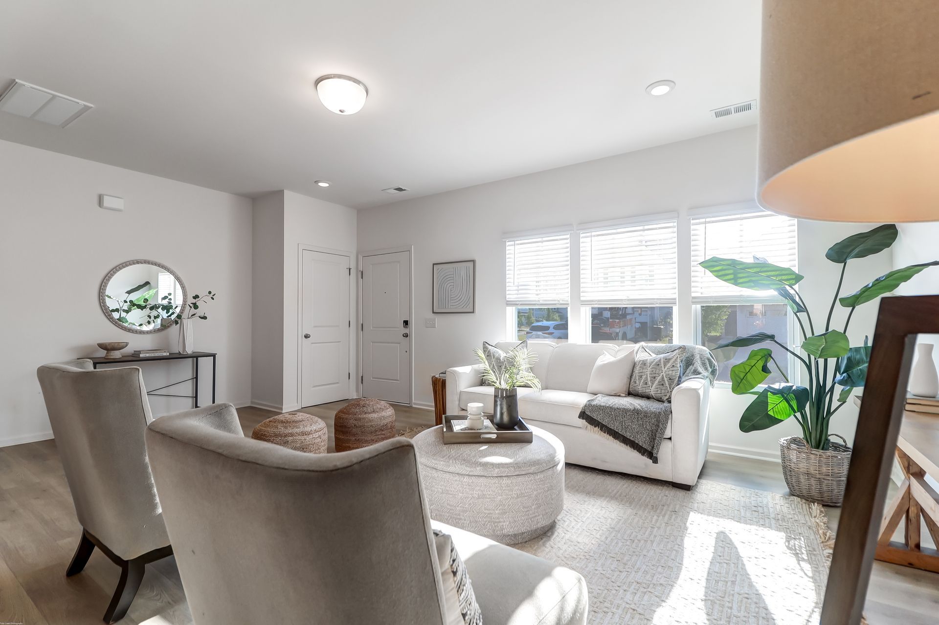 A living room with a couch , chairs , a coffee table and a mirror.