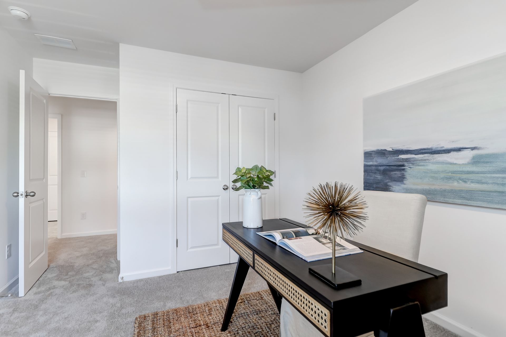 A home office with a desk , chair and painting on the wall.