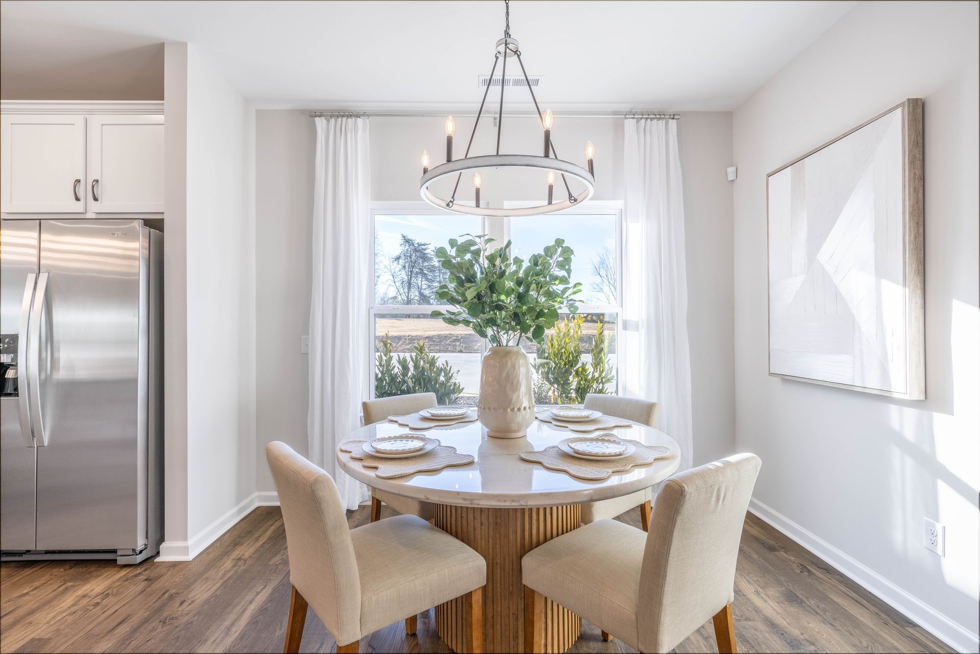 A dining room with a round table and chairs and a chandelier.