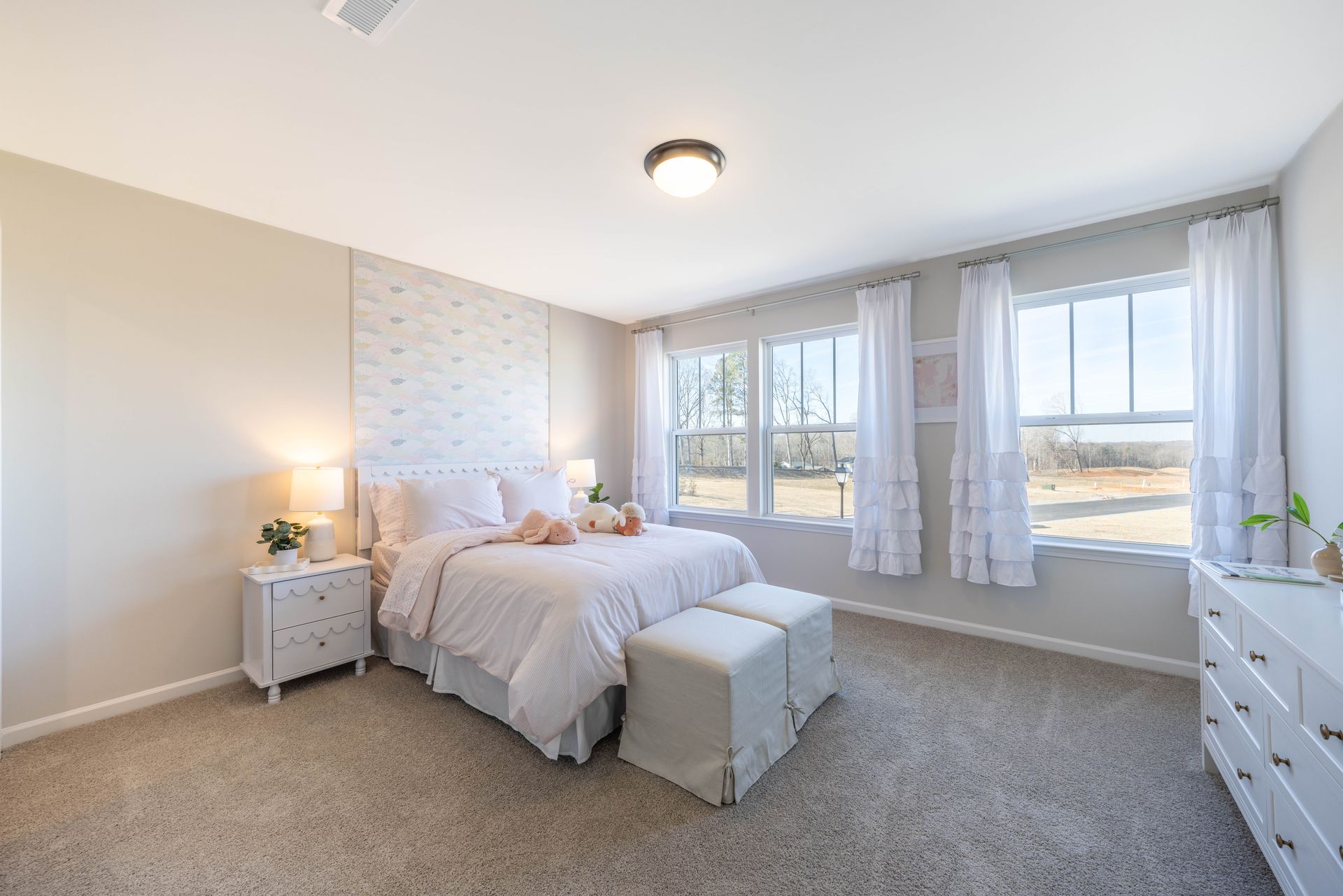 A bedroom with a bed , dresser , nightstand and two windows.