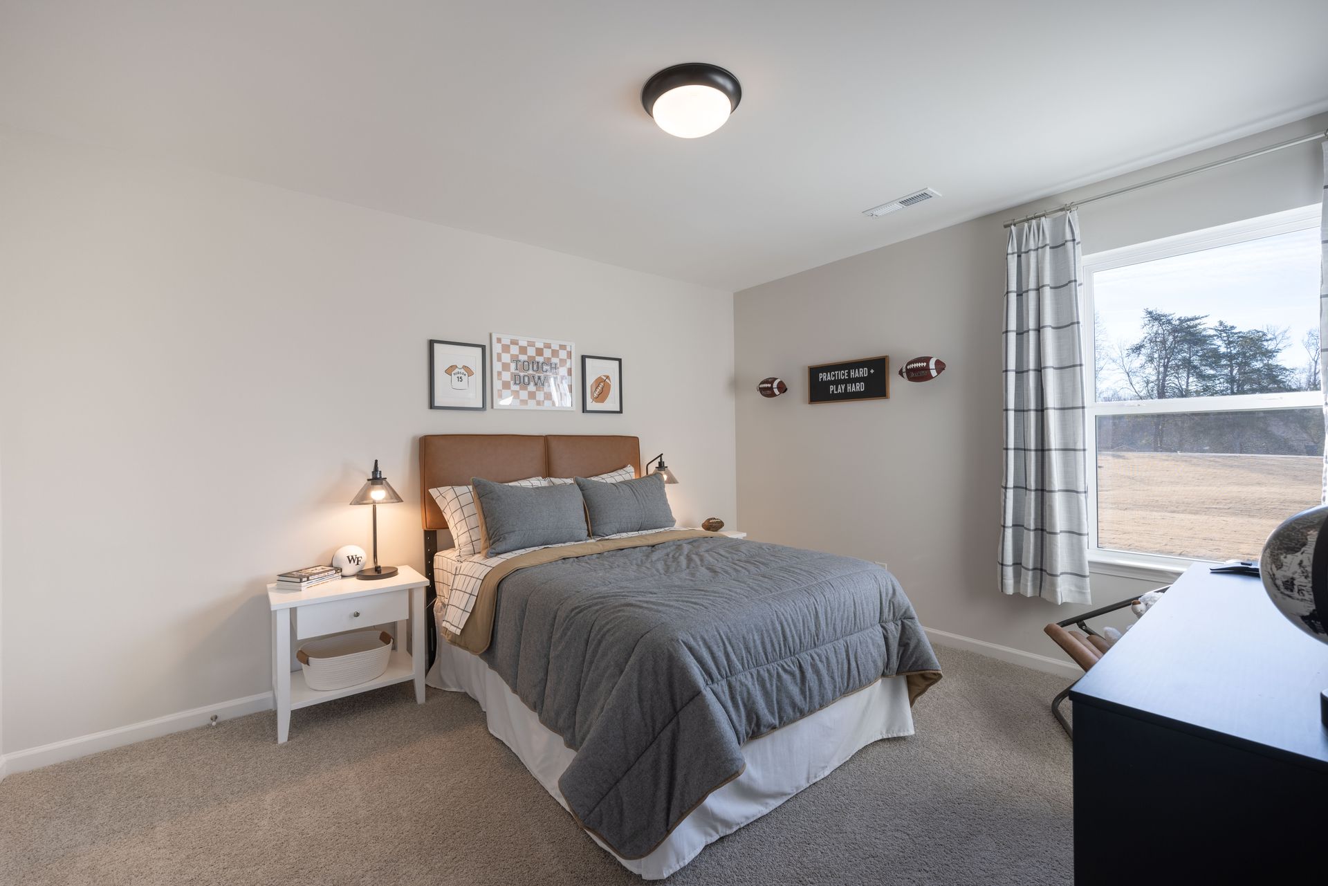 A bedroom with a bed , nightstand , dresser and window.