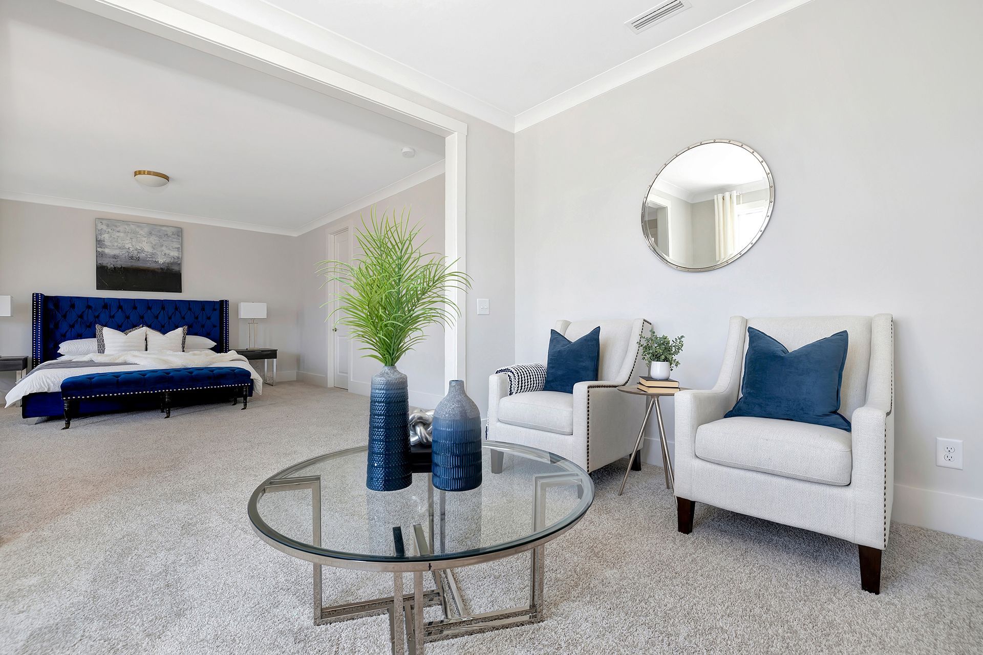 A living room with two chairs , a coffee table and a mirror.