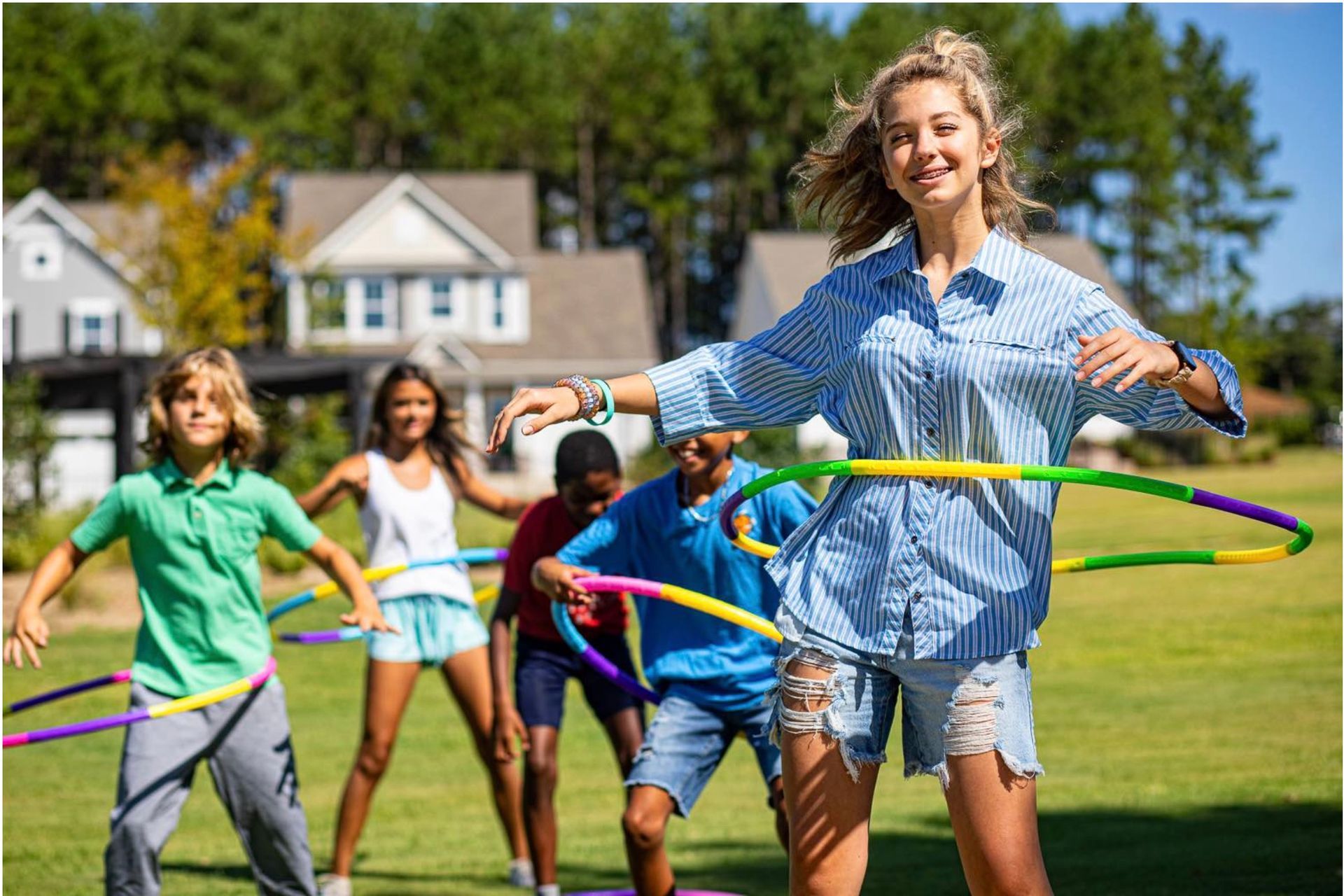 A group of children are playing with hula hoops in a field.