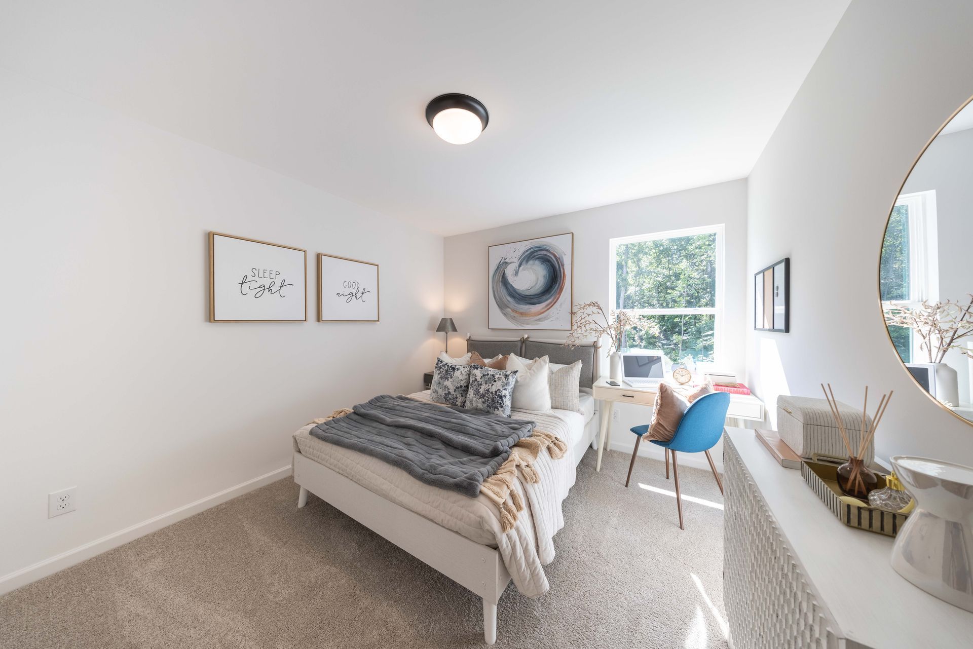 A bedroom with a bed , desk , chair and mirror.