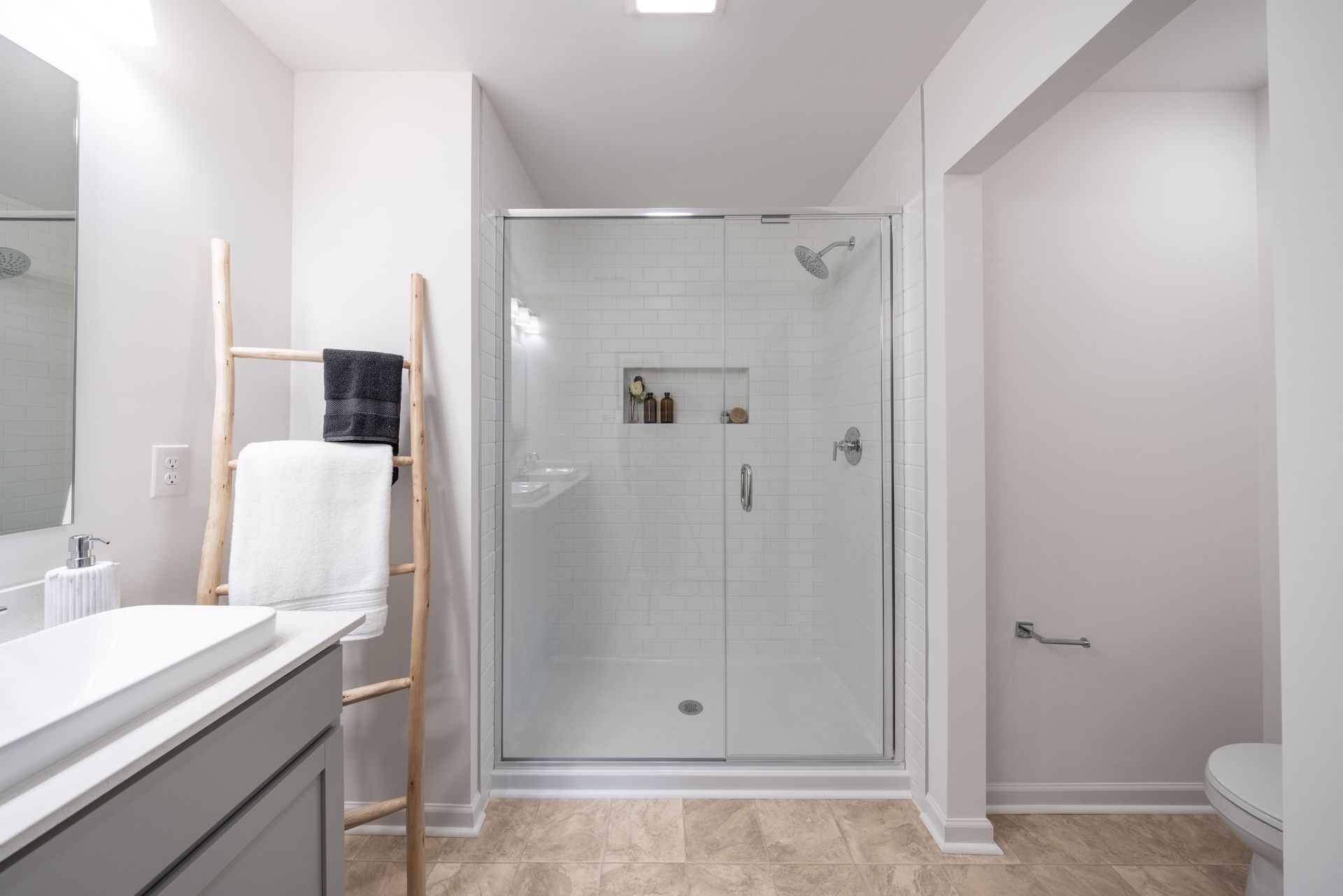 A bathroom with a walk in shower , sink , toilet and mirror.