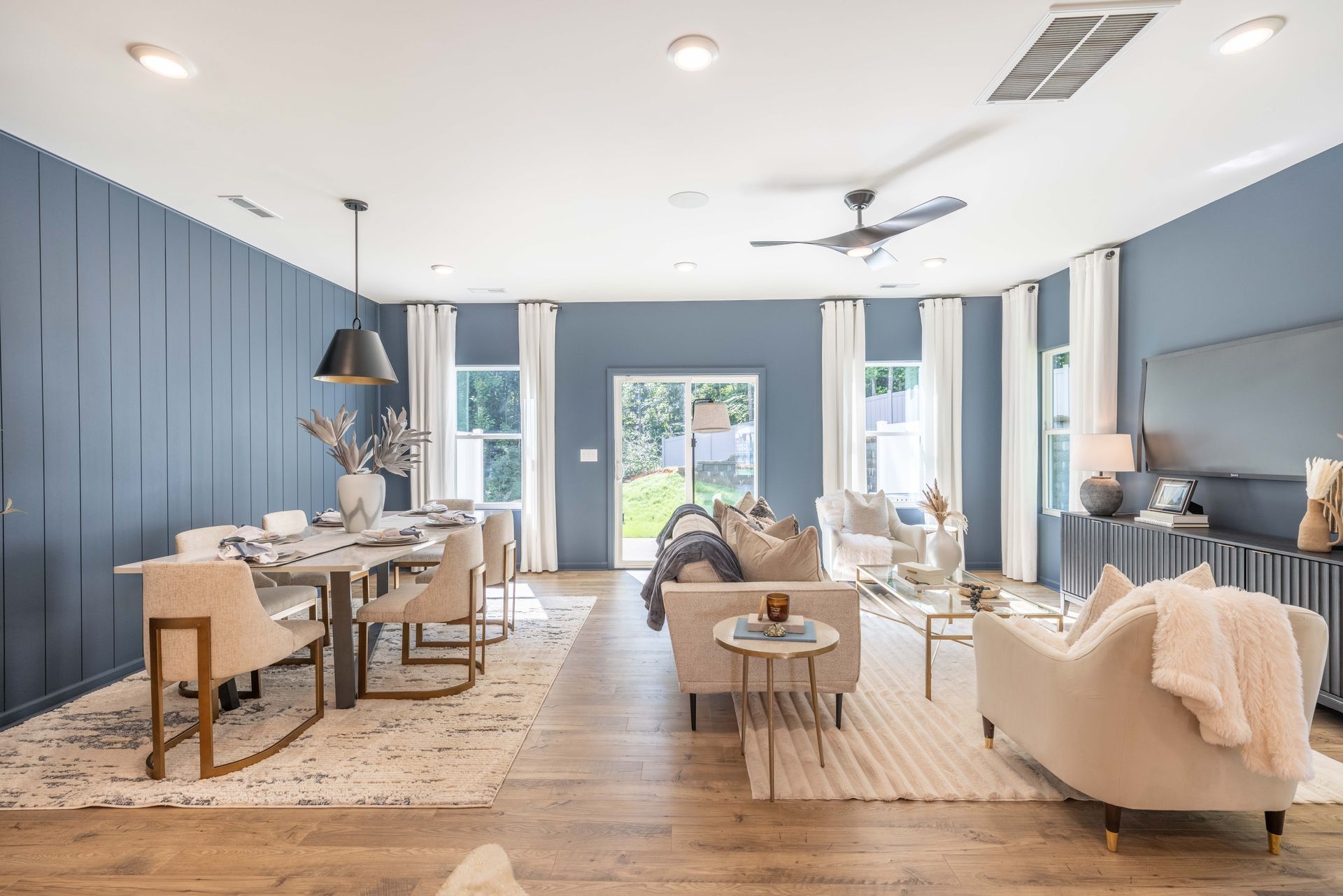 A living room with a couch , chairs , a table and a ceiling fan.