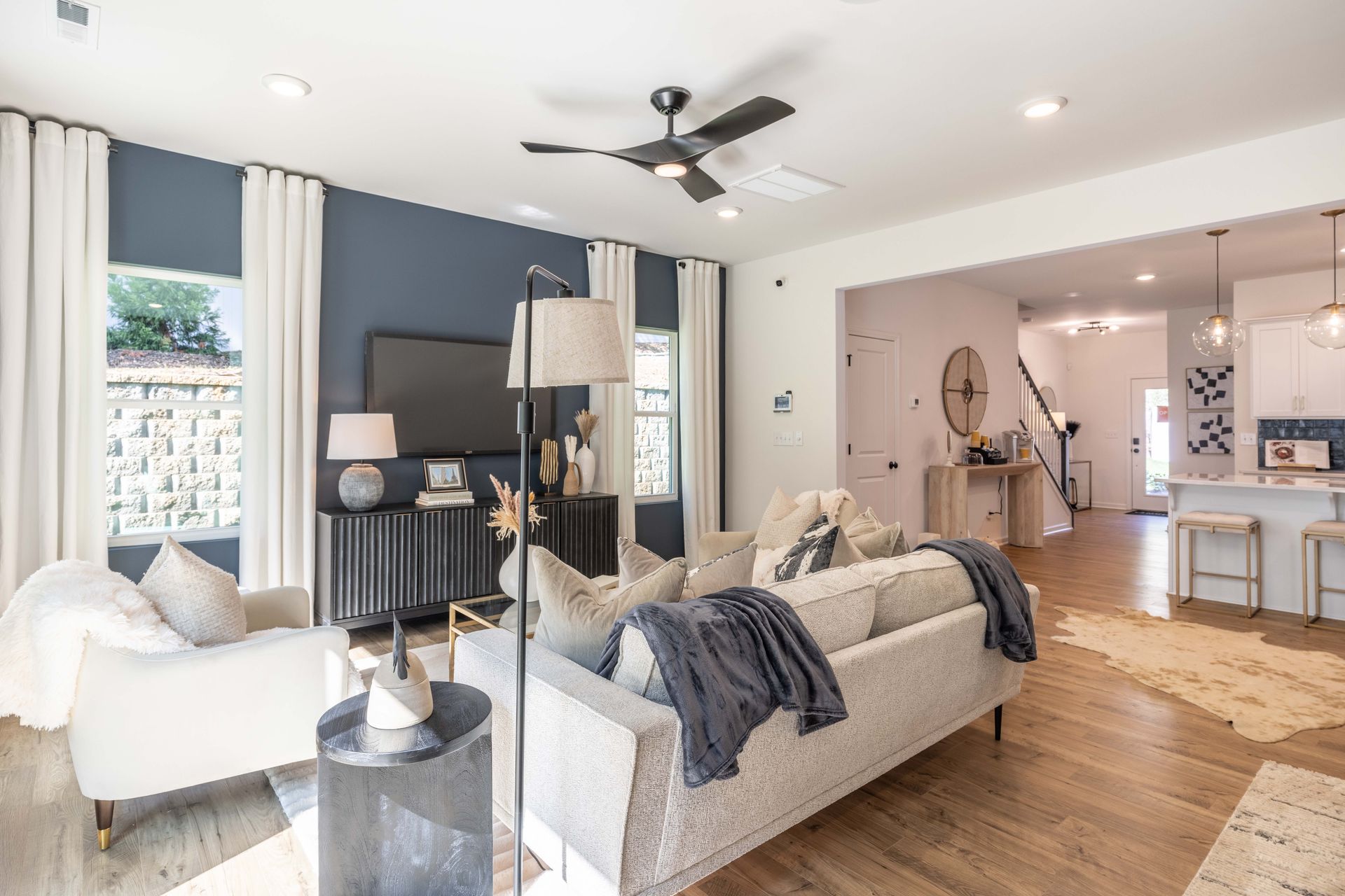 A living room with a couch , chairs , and a ceiling fan.